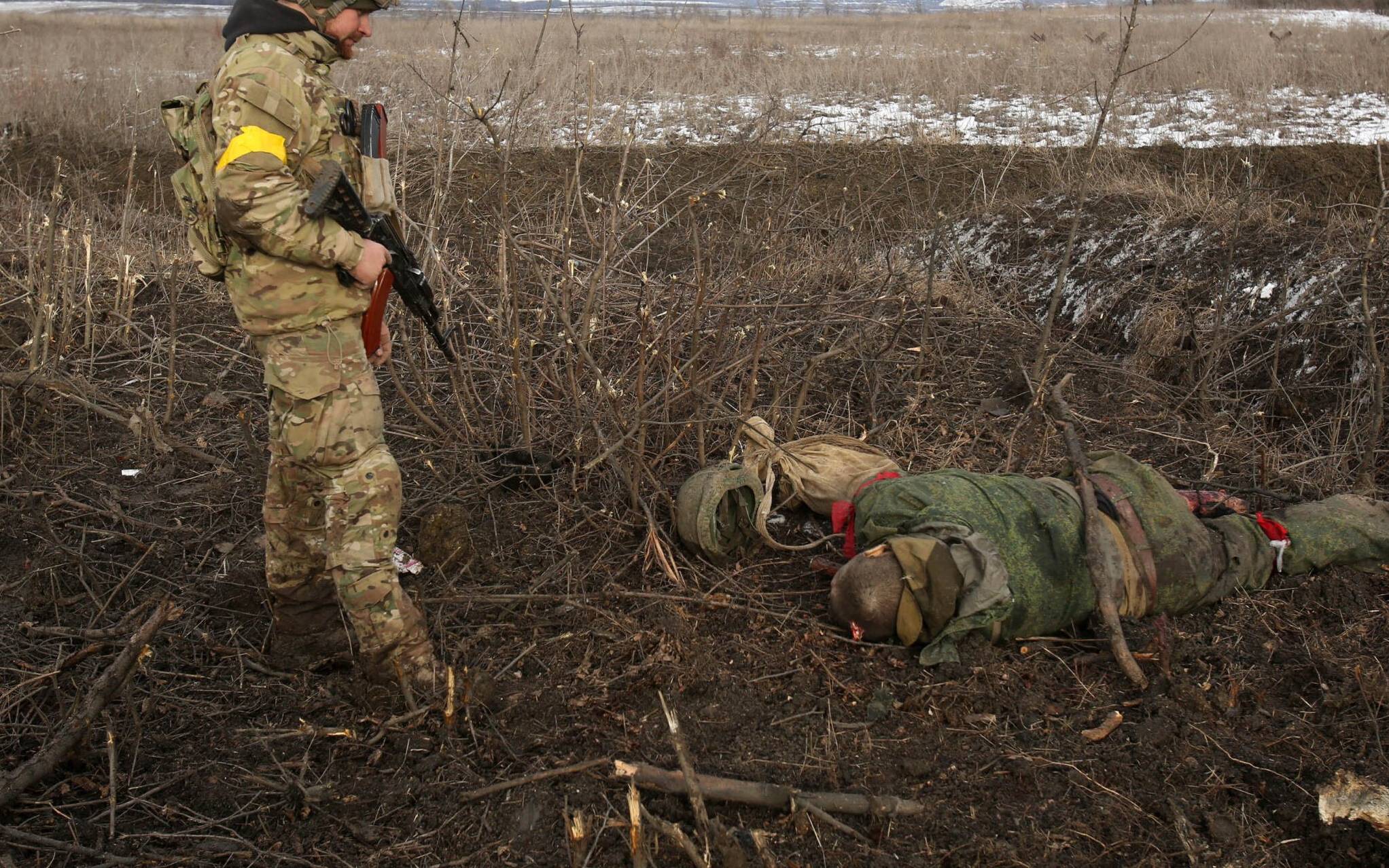EDITORS NOTE: Graphic content / A serviceman of the Ukrainian Military Forces examines a body following fighting against Russian troops and Russia-backed separatists near the village of Zolote, Lugansk region on March 6, 2022. - Russia's invasion of Ukraine, now in its eleventh day, has seen more than 1.5 million people flee the country in what the UN has called "Europe's fastest growing refugee crisis since World War II". (Photo by Anatolii Stepanov / AFP)