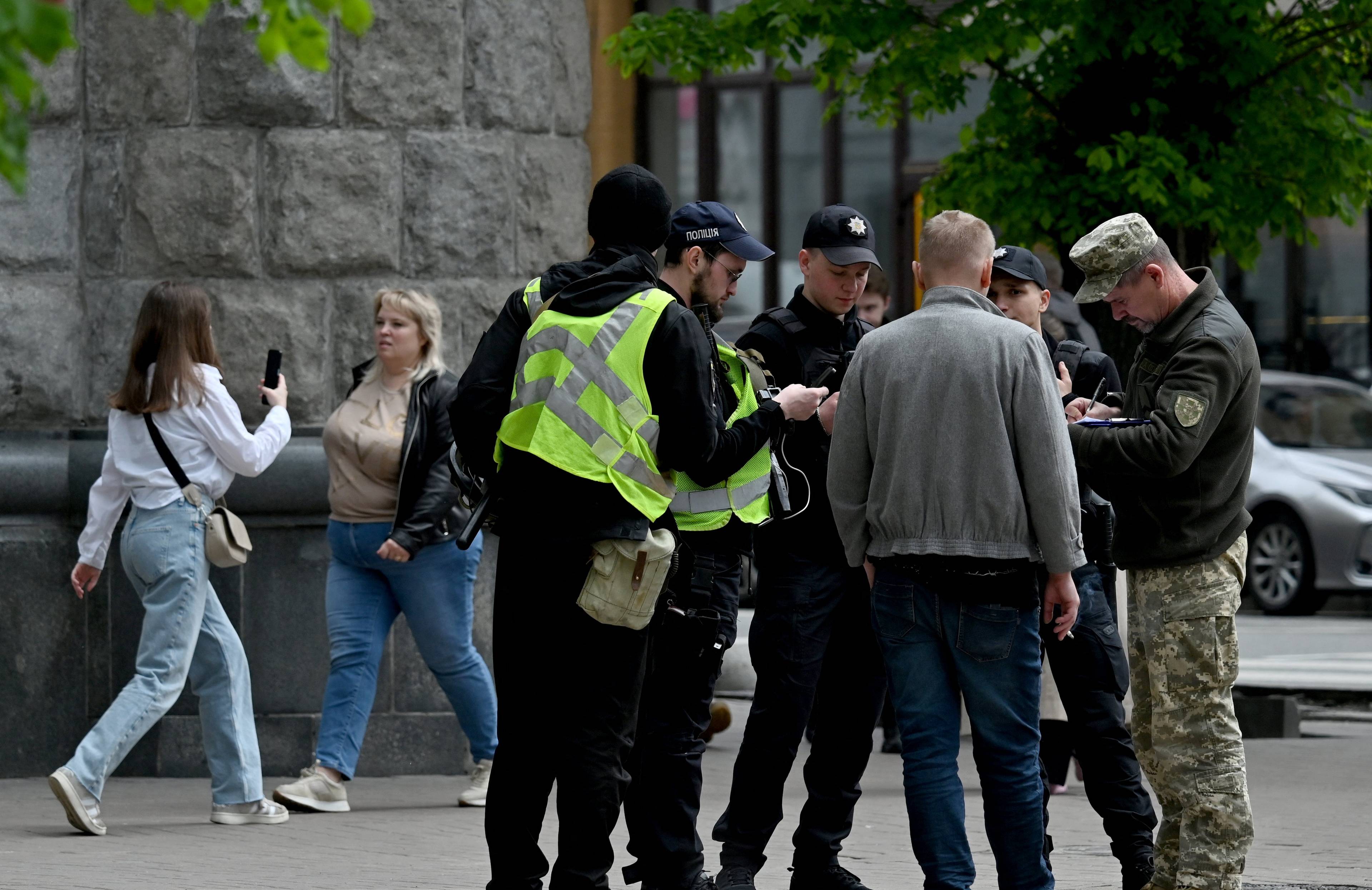 grupa mężczyzn otoczona na ulicy przez żołnierzy, którzy sprawdzają ich dokumenty. Mobilizacja w Ukrainie