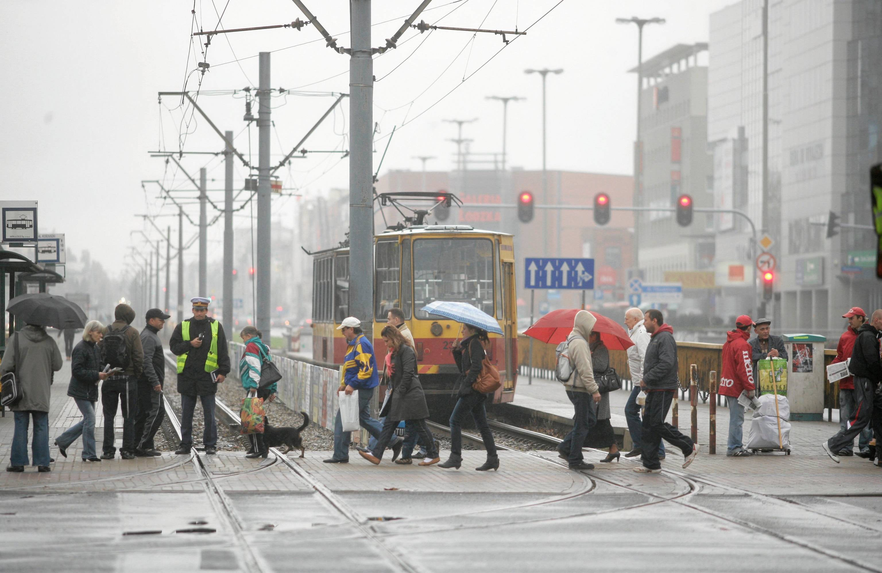 Ludzie przechodzą przez jezdnię, stoi tramwaj