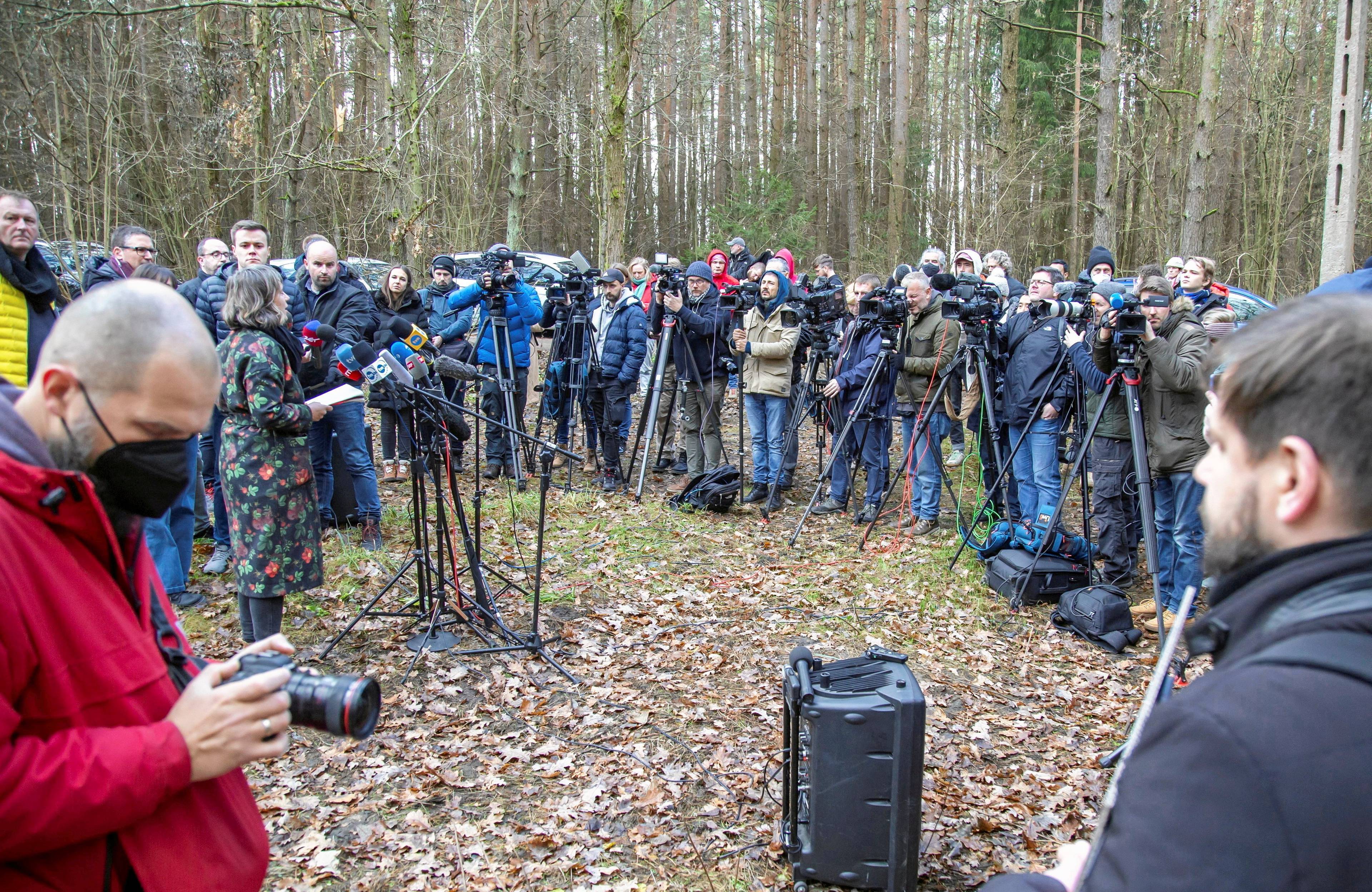 Grupa dziennikarzy z mikrofonami w lesie patrzy na aktywistów
