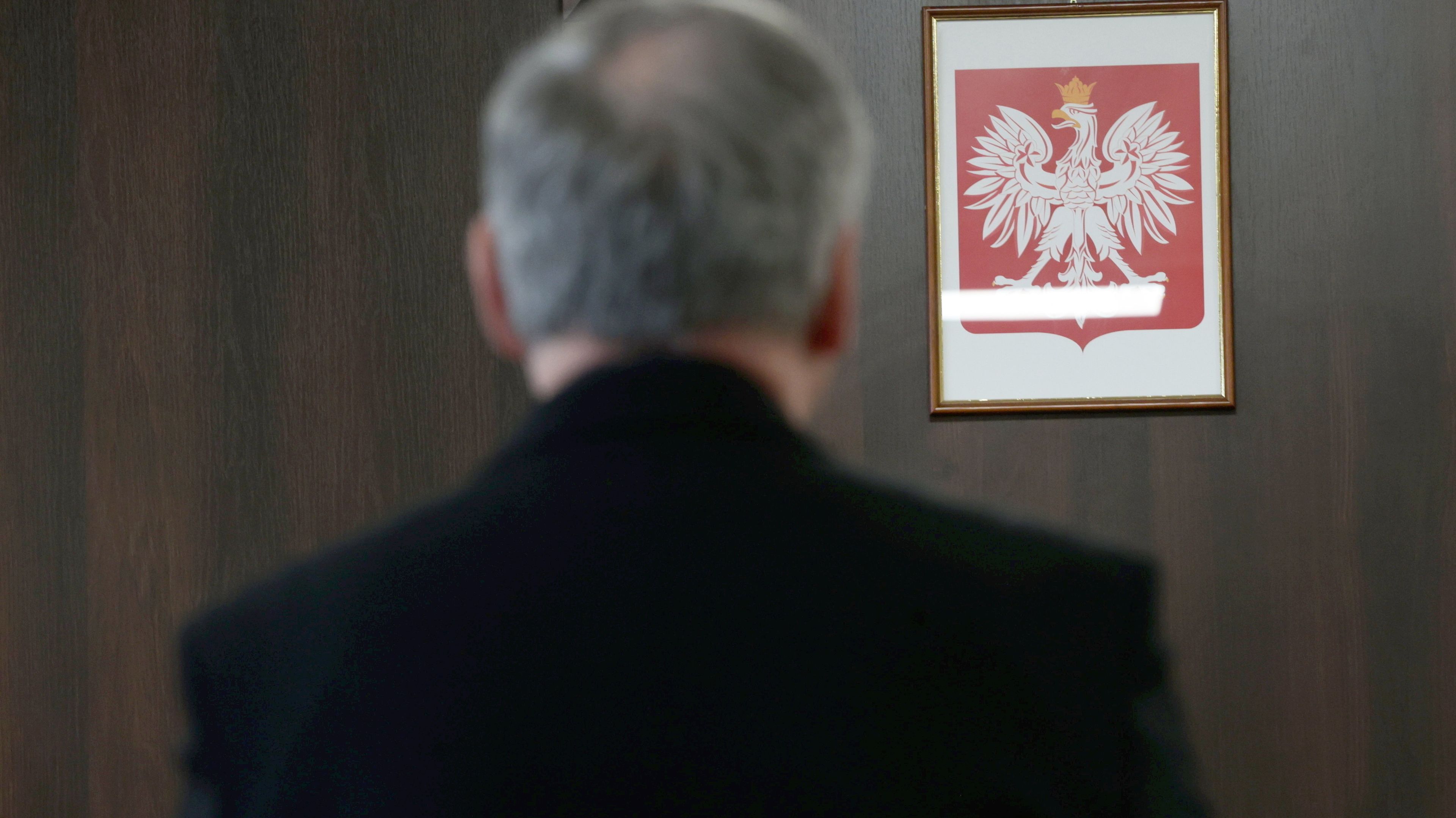 Mężczyzna stoi tyłem. Przed nim godło Polski