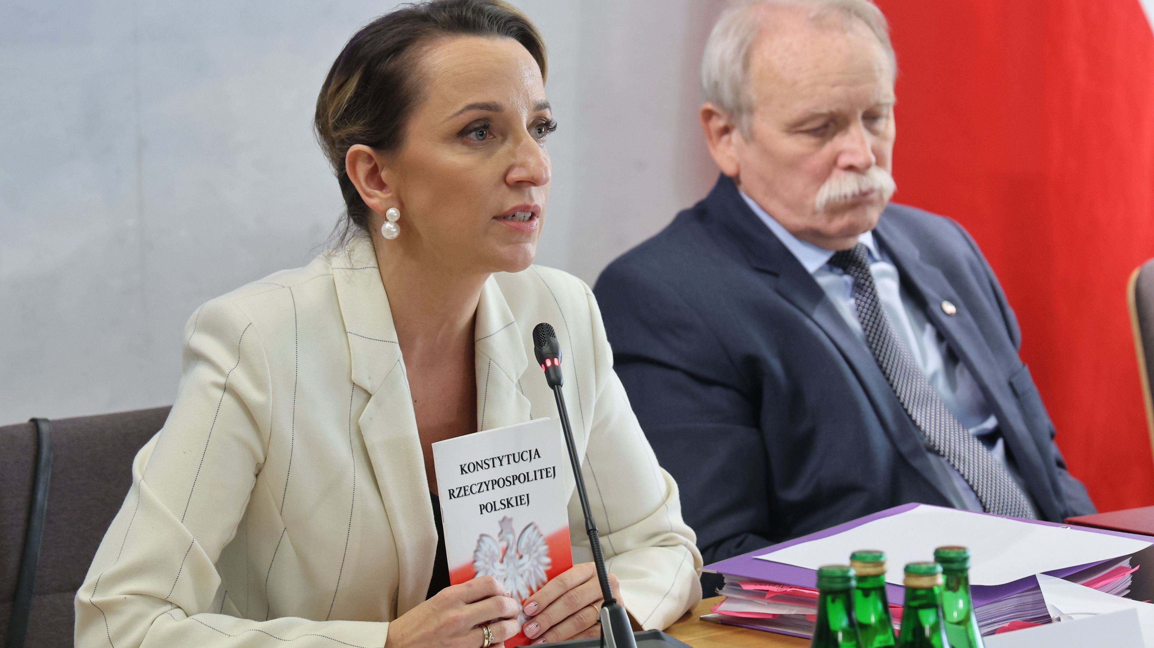 Ciemnowłosa kobieta w jasnym żakiecie i siwy mężczyzna w ciemnej marynarce