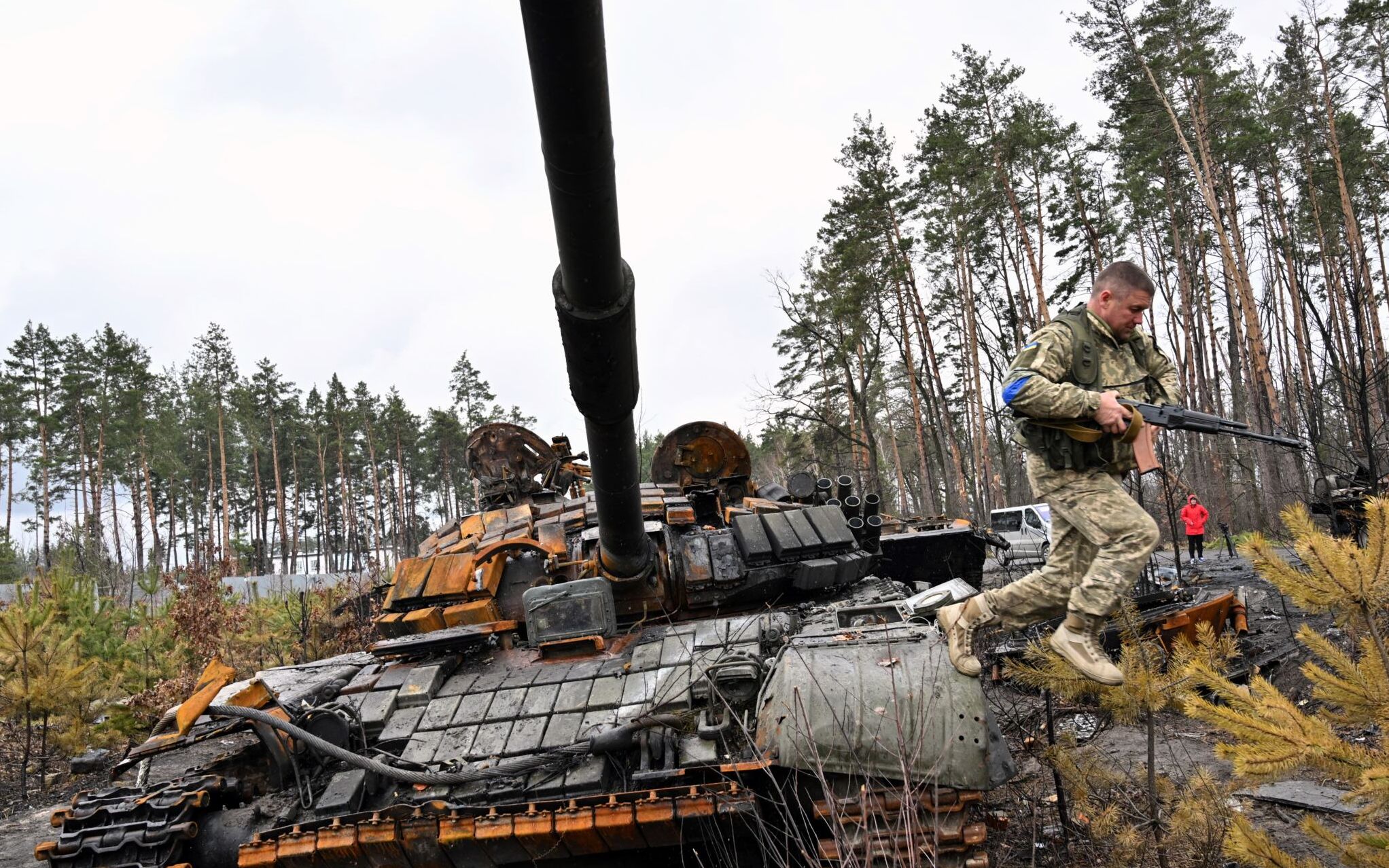 A Ukrainian serviceman jumps off a destroyed Russian army tank, not far from the Ukrainian capital of Kyiv on April 3, 2022. - Europe's worst conflict in decades, sparked by Russia's invasion on February 24, has already left some 20,000 people dead, according to Ukrainian estimates. (Photo by Sergei SUPINSKY / AFP)