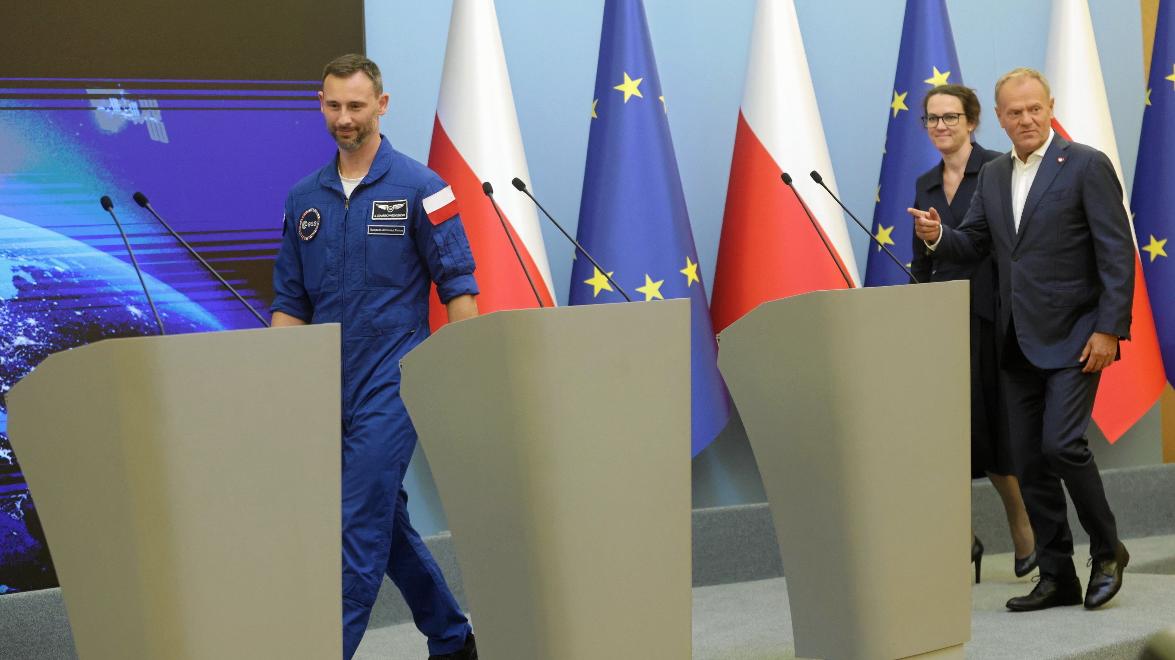 Sławosz Uznański Wiśniewski, Donald Tusk i Marta Wachowicz (szefowa POLSA) wchodzą do sali, gdzie odbywała się konferencja prasowa po lądowaniu misji Ignis