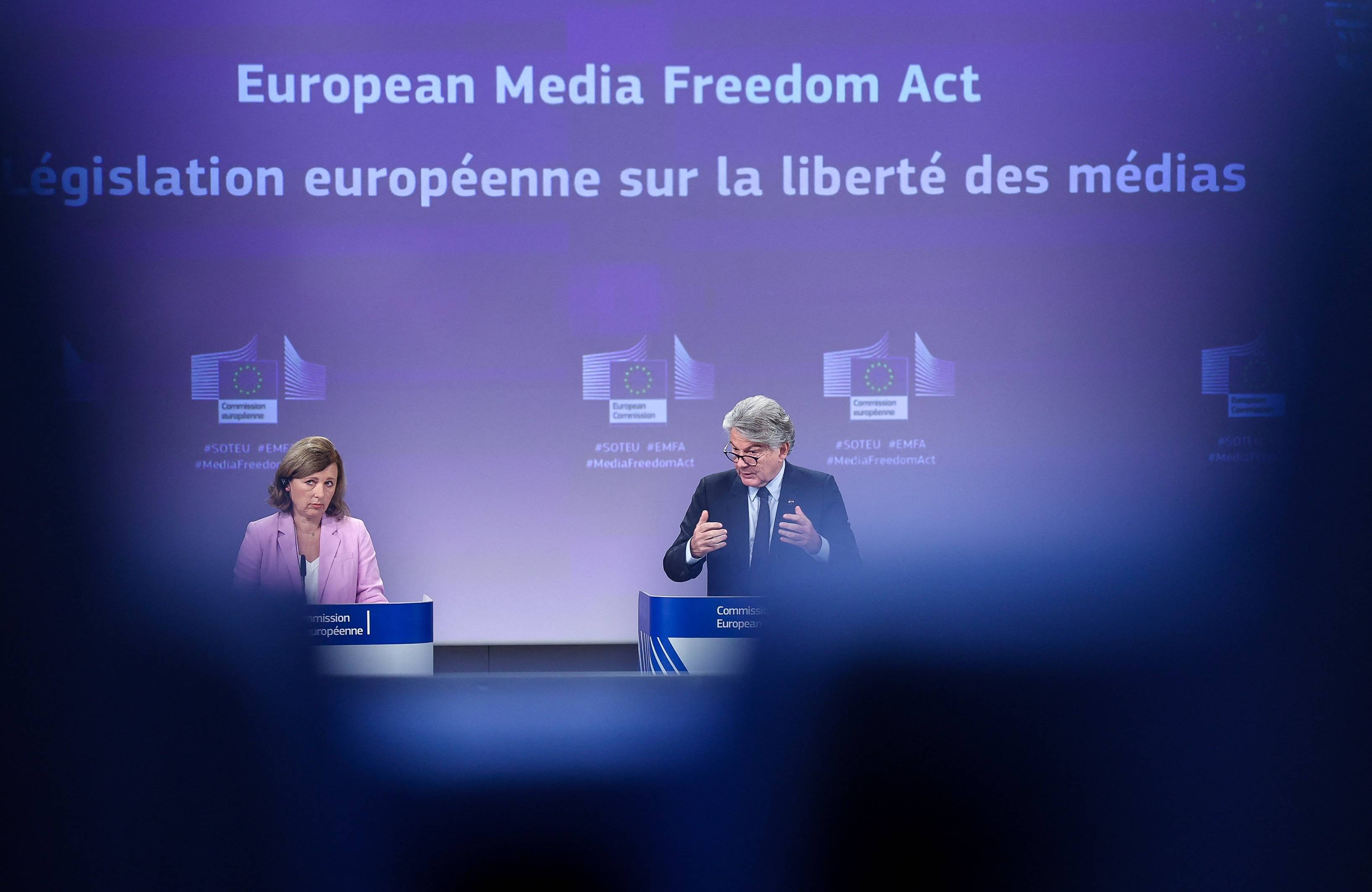 Dwoje polityków i napis na niebieskiej tablicy po angielsku i francusku (Europejski Akt o Wolności Mediów)