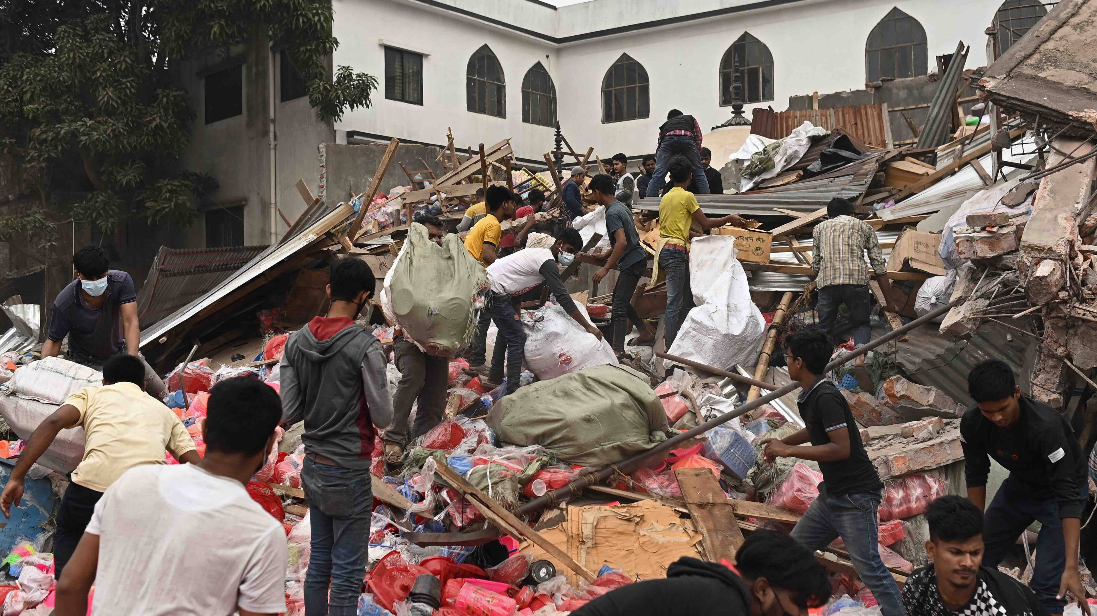 Ludzie szukają rzeczy wśród szczątków zburzonych domów. Bangladesz