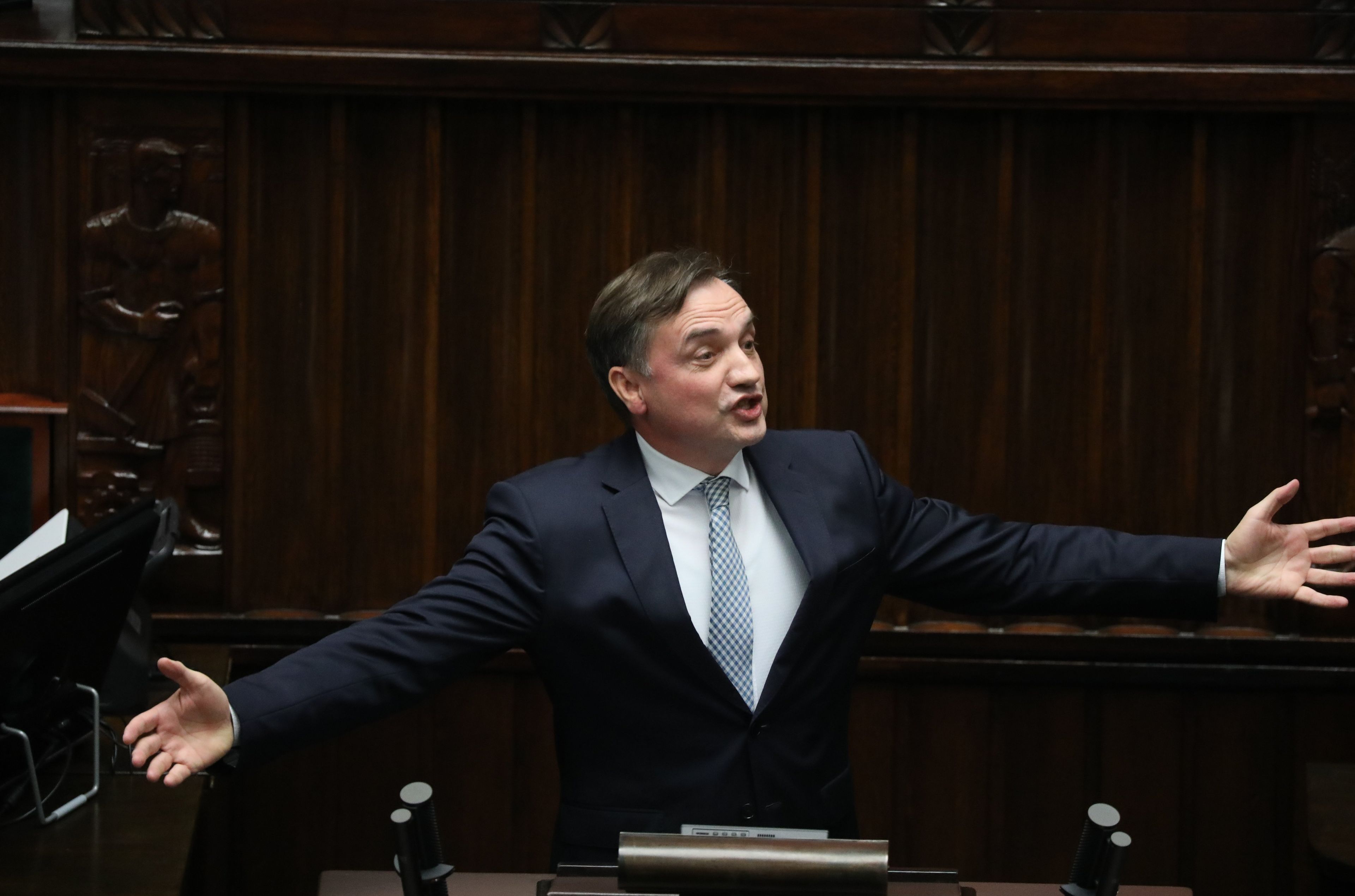 Mężczyzna na trybunie sejmowej rozkłada ręce