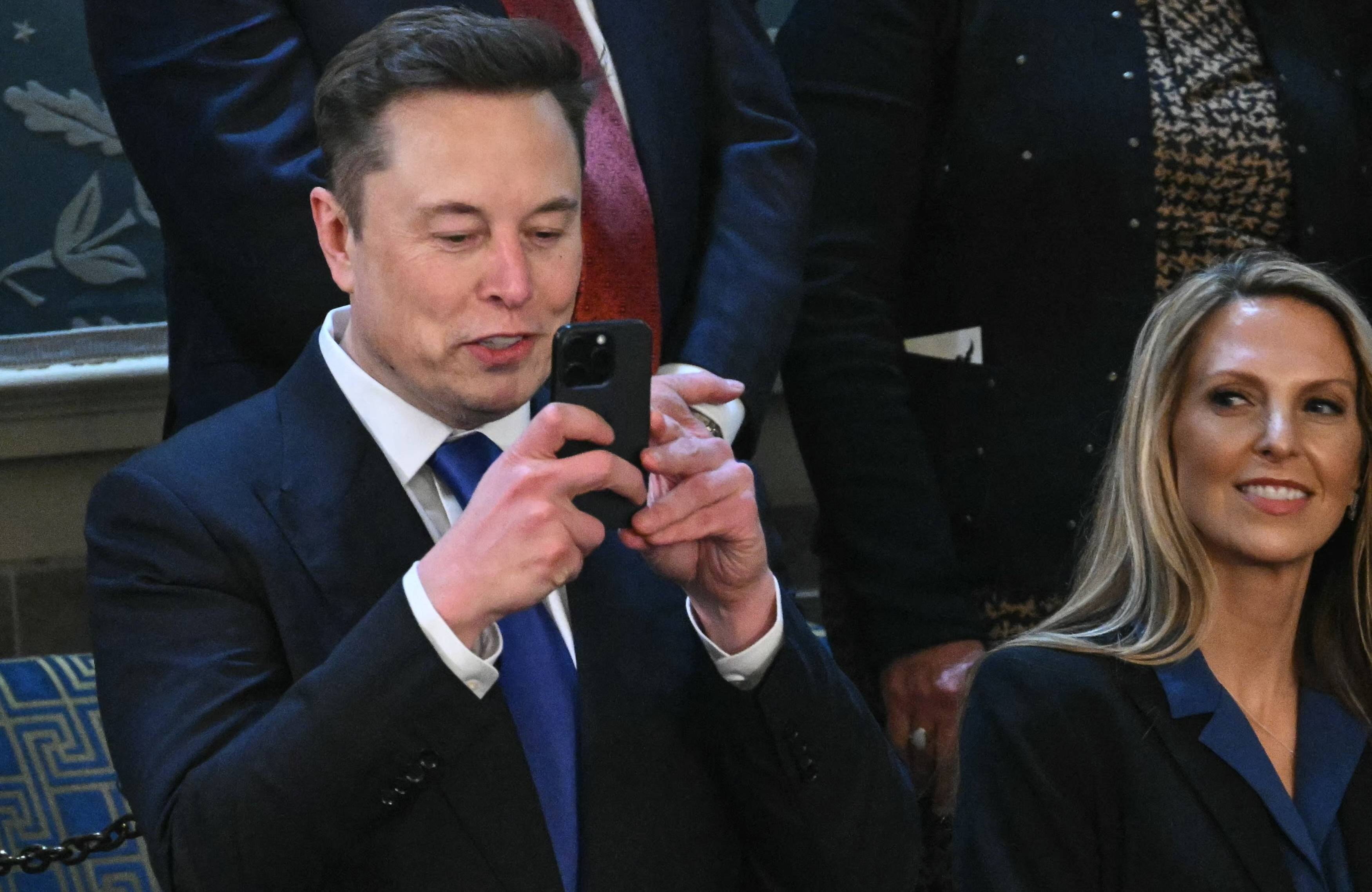 Mężczyzna przed pięćdziesiątką klika coś na telefonie albo robi zdjęcie. Elon Musk w amerykańskim Kongresie.