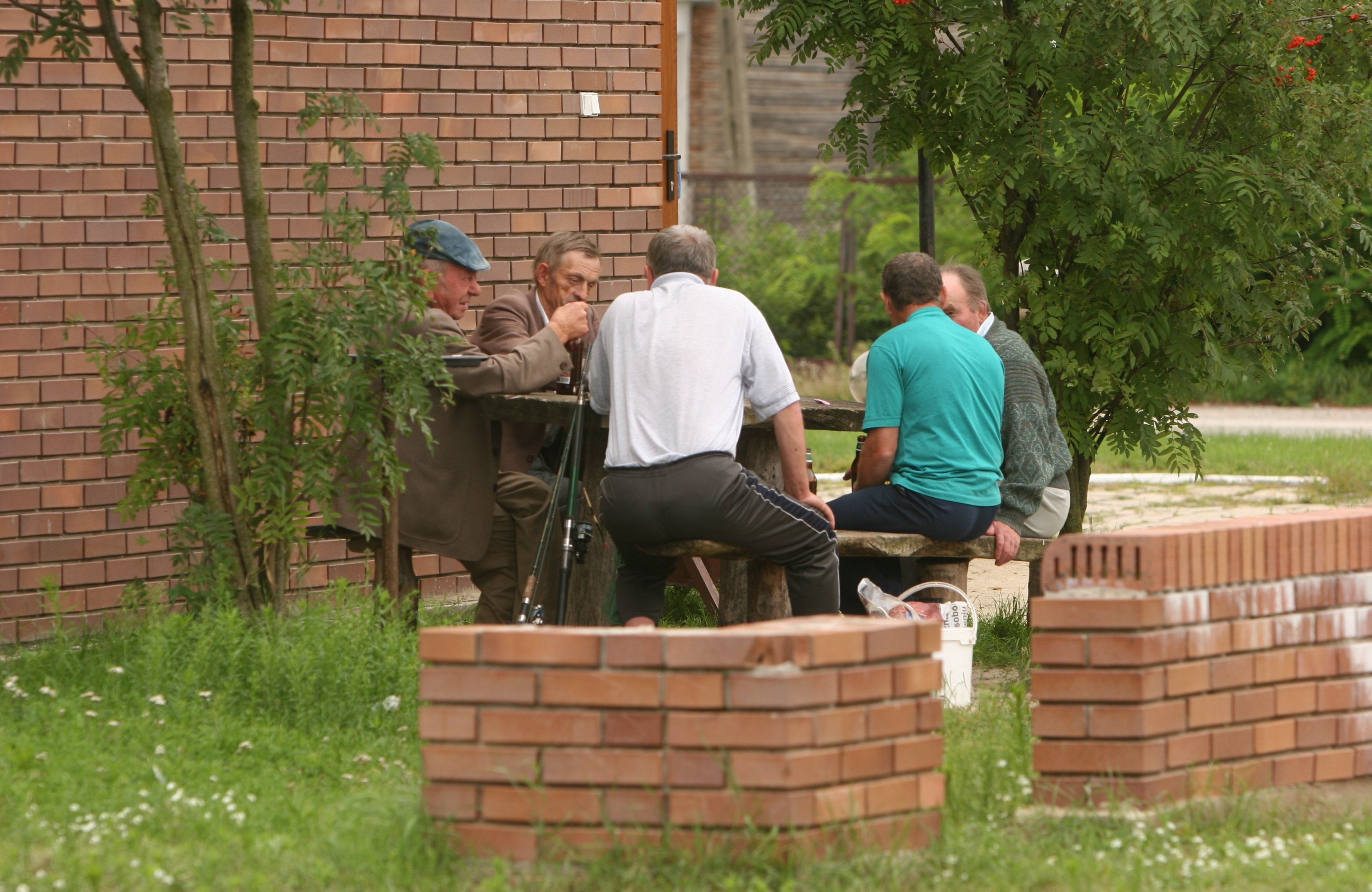 mężczyźni siedzący w koło na ceglanym murku