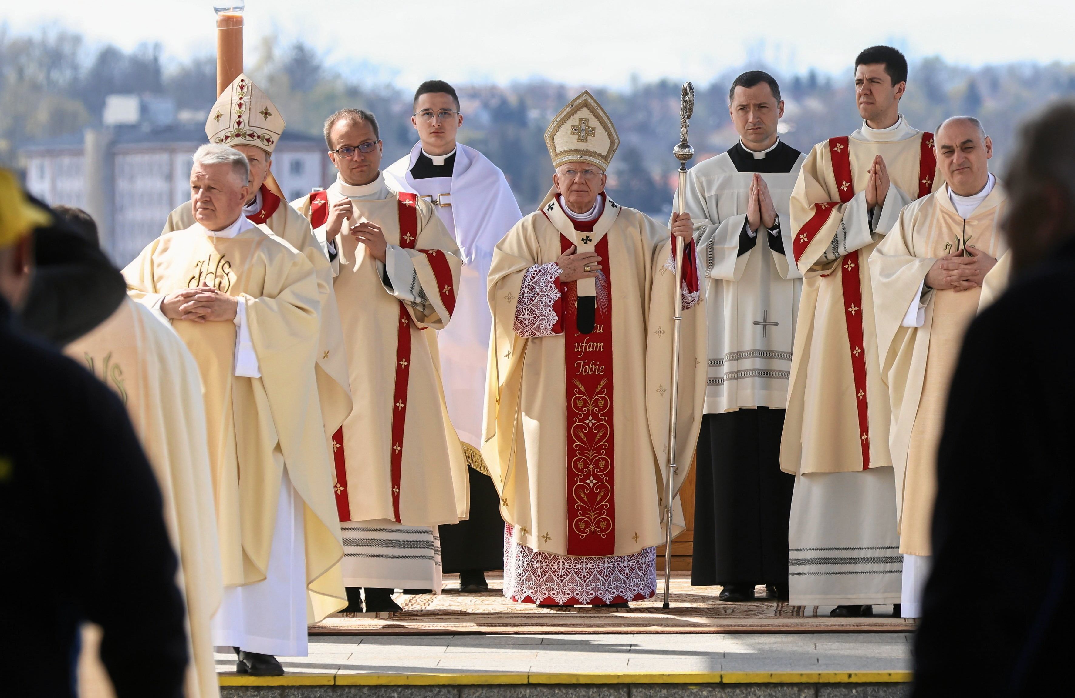 Biskupi kościoła katolickiego w złotych szatach liturgicznych, ręce mają złożone do modlitwy