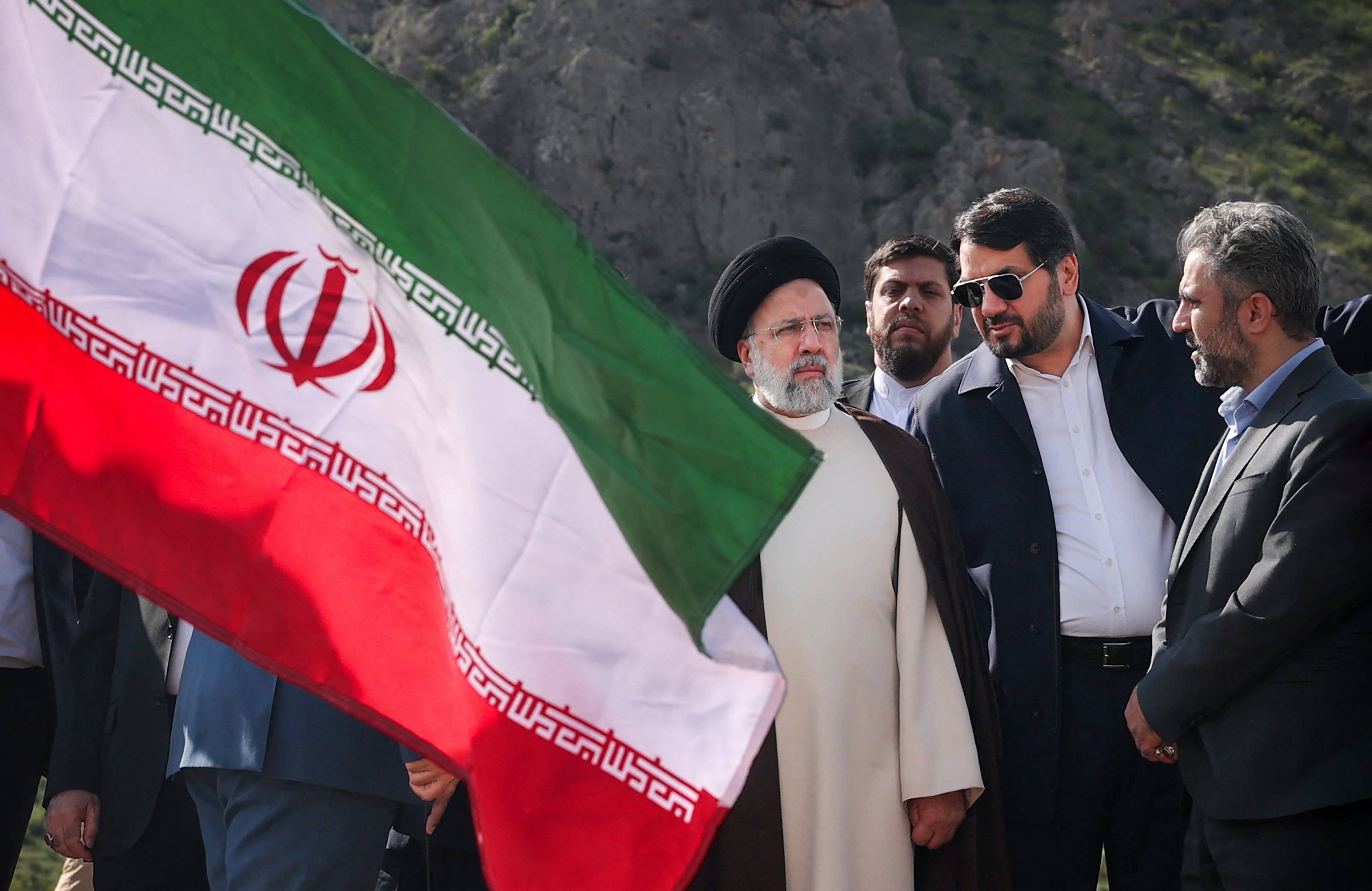 Prezydent Iranu stoi w otoczeniu mężczyzn na budowie tamy, obok widać flagę irańską