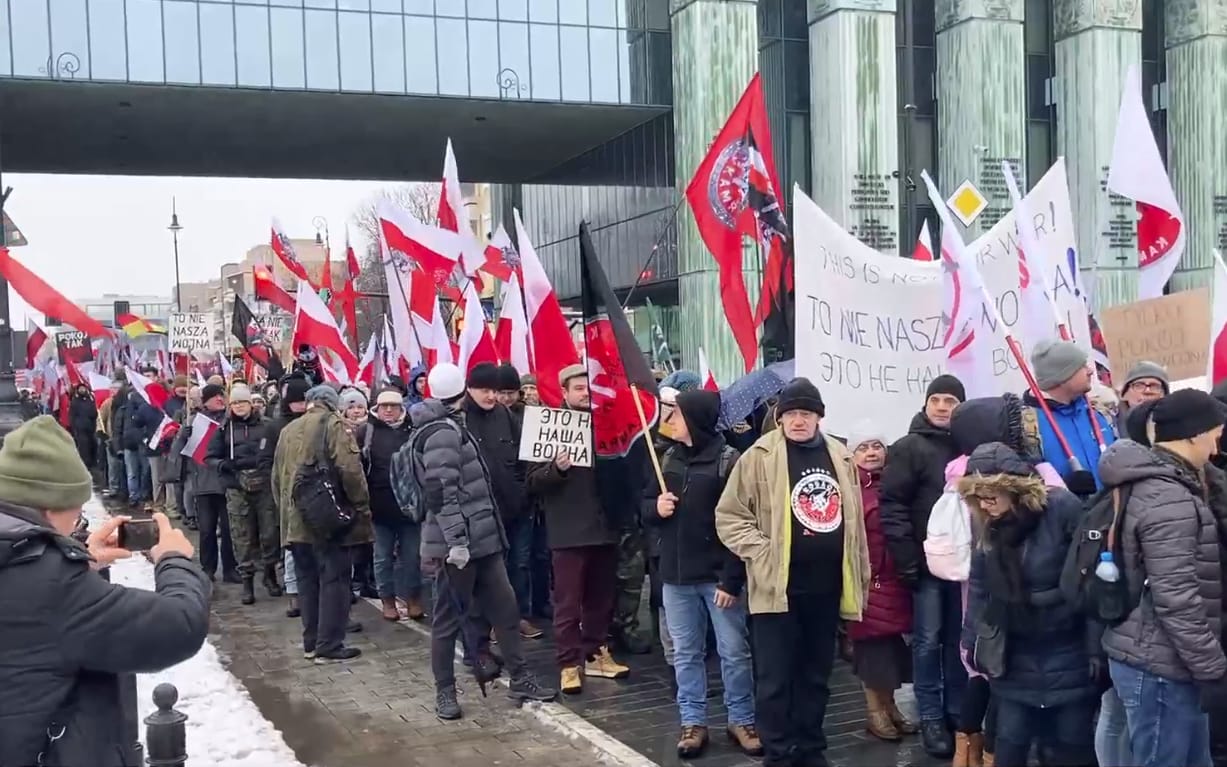 Tłum z białoczerwonymi flagami i banerem z napisem To nie nasza wojna