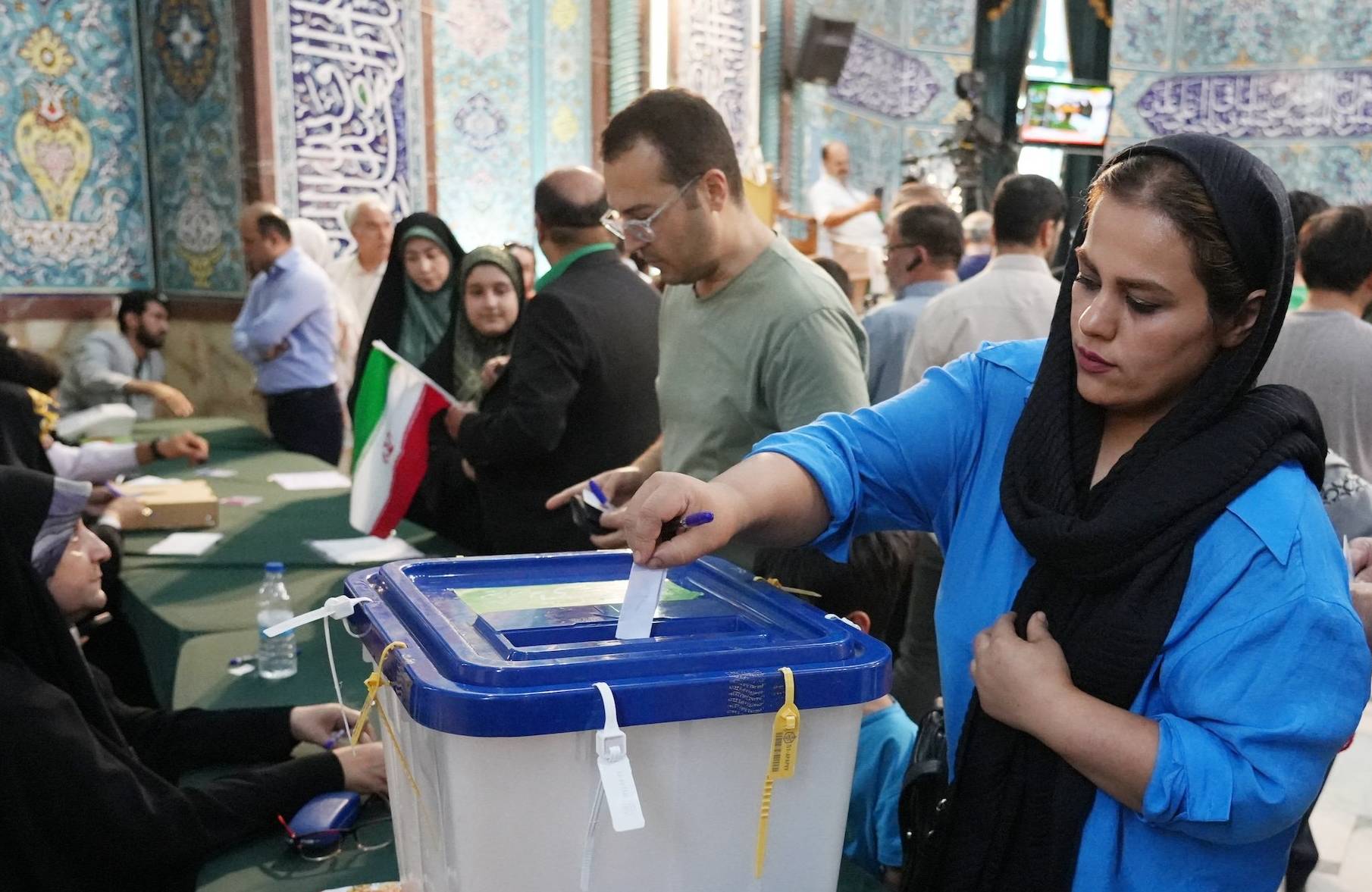 Kobiety i mężczyźni wrzucają głosy do urn wyborczych podczas wyborów prezydenckich w Iranie