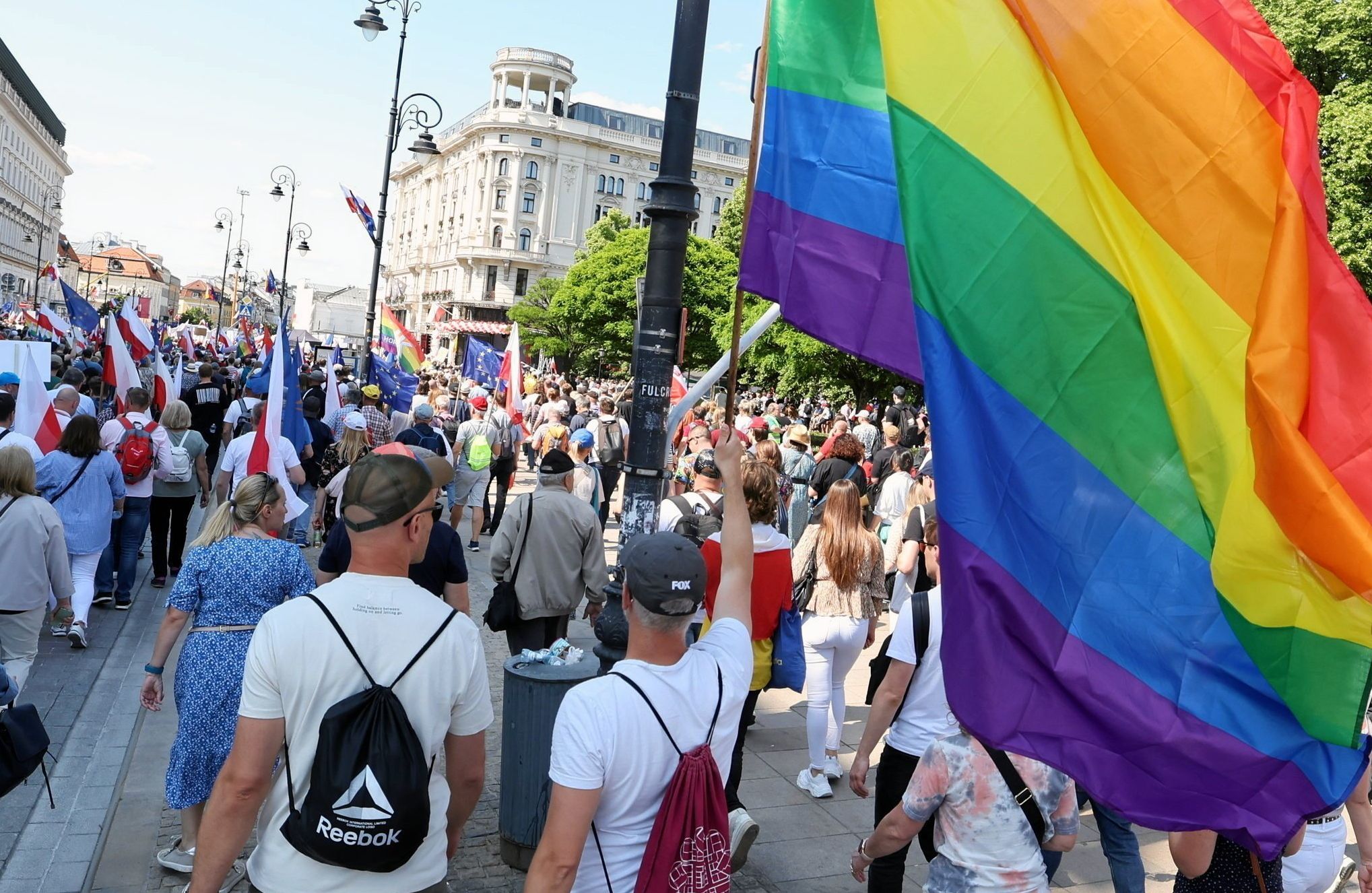 Demonstranci niosą tęczową flagę podczas marszu 4 czerwca w centrum Warszawy