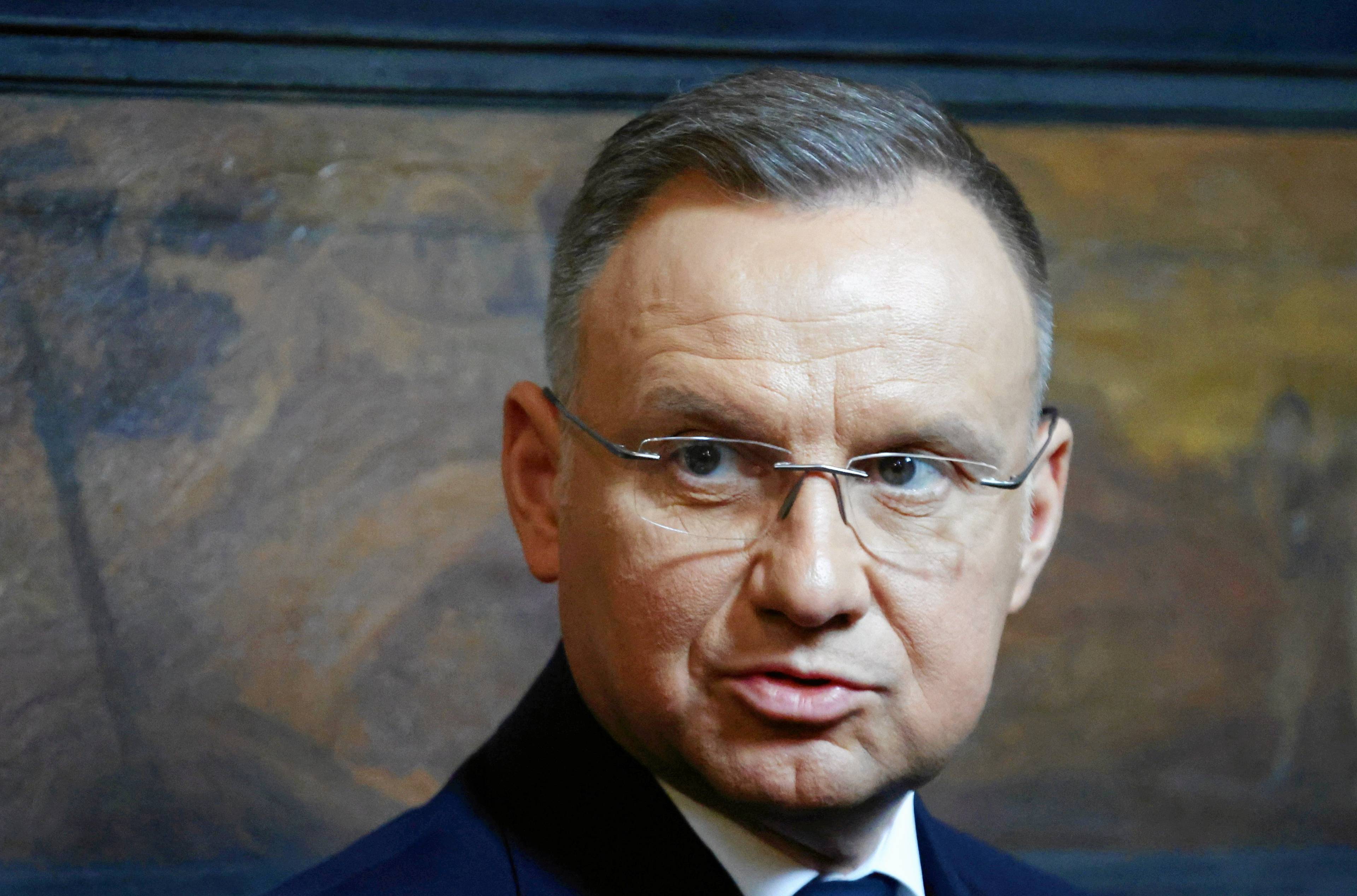 Portret Andrzeja Dudy w okularach i płaszczu. Prezydent spogląda w lewą stronę