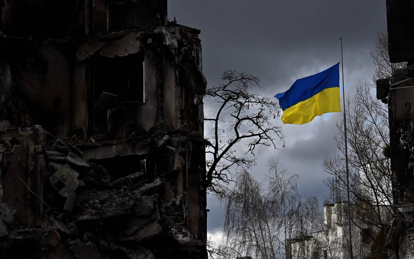 The Ukrainian flag flutters between buildings destroyed in bombardment, in the Ukrainian town of Borodianka, in the Kyiv region on April 17, 2022. - Russia invaded Ukraine on February 24, 2022. (Photo by Sergei SUPINSKY / AFP)