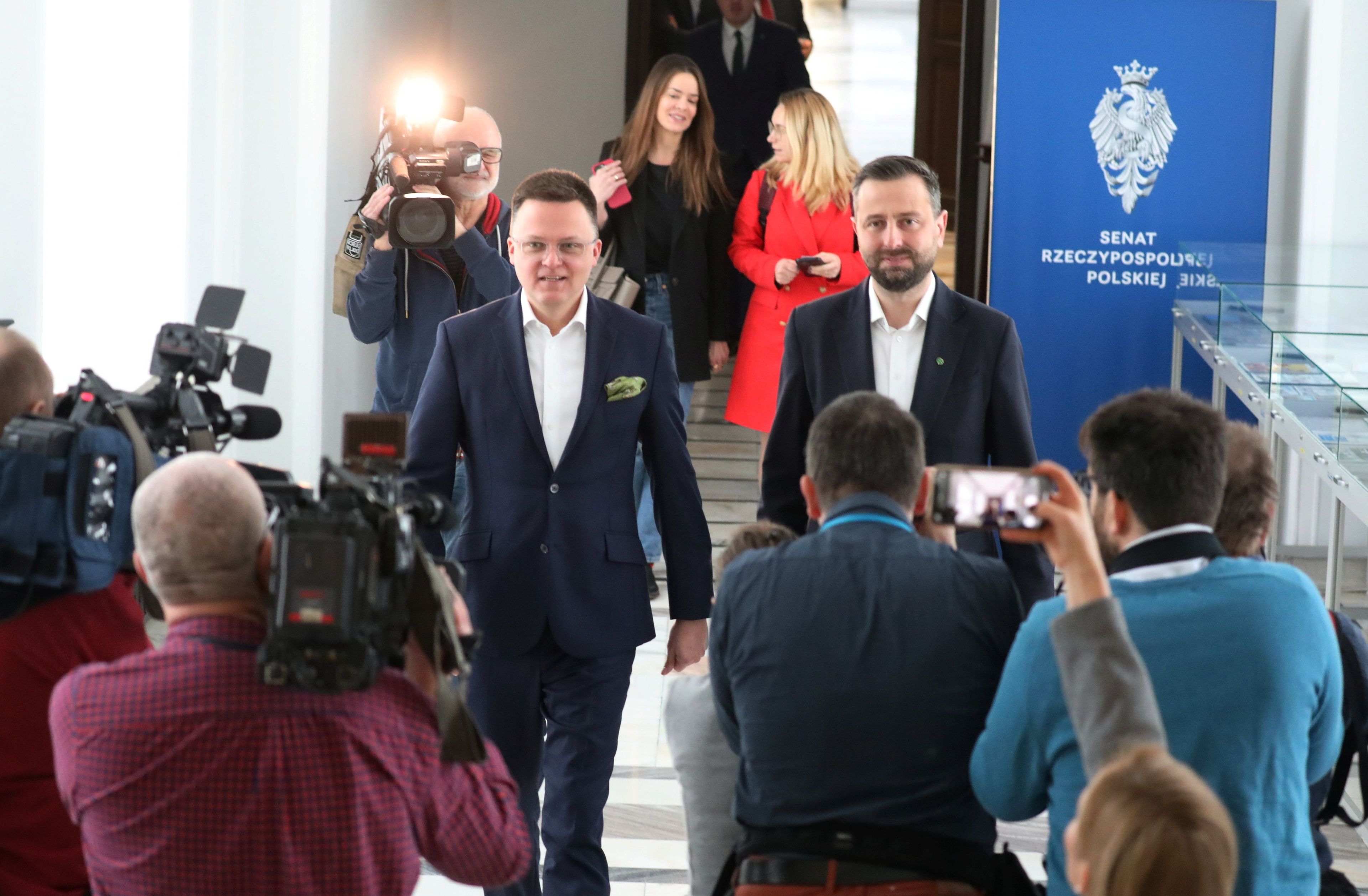 Szymon Hołownia i Władysław Kosiniak-Kamysz idą przez korytarz sejmowy, otoczeni dziennikarzy