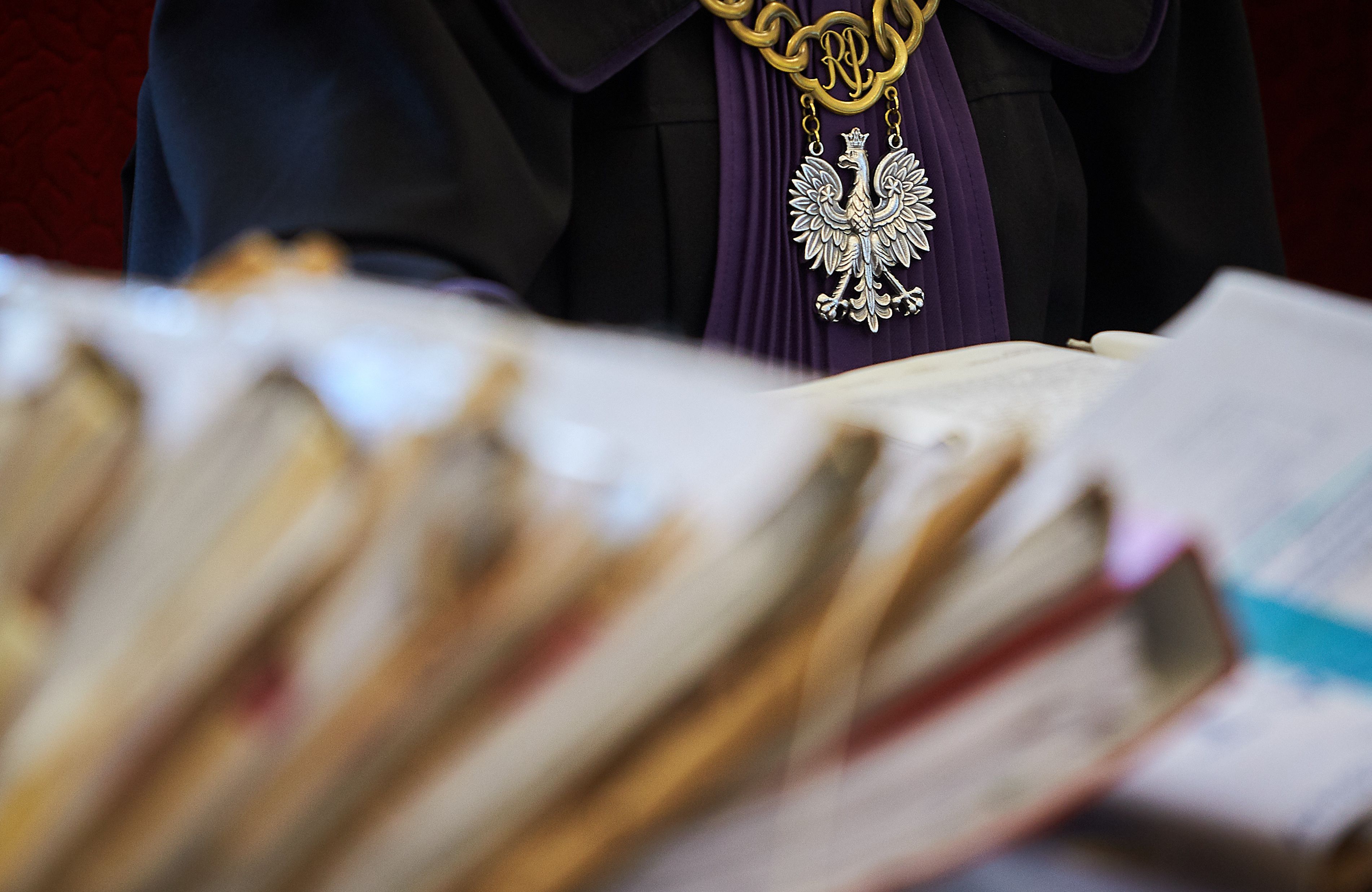 Akta sprawy i zarys sylwetki w todze, ż łańcuchem sedziego (z orłem w koronie)