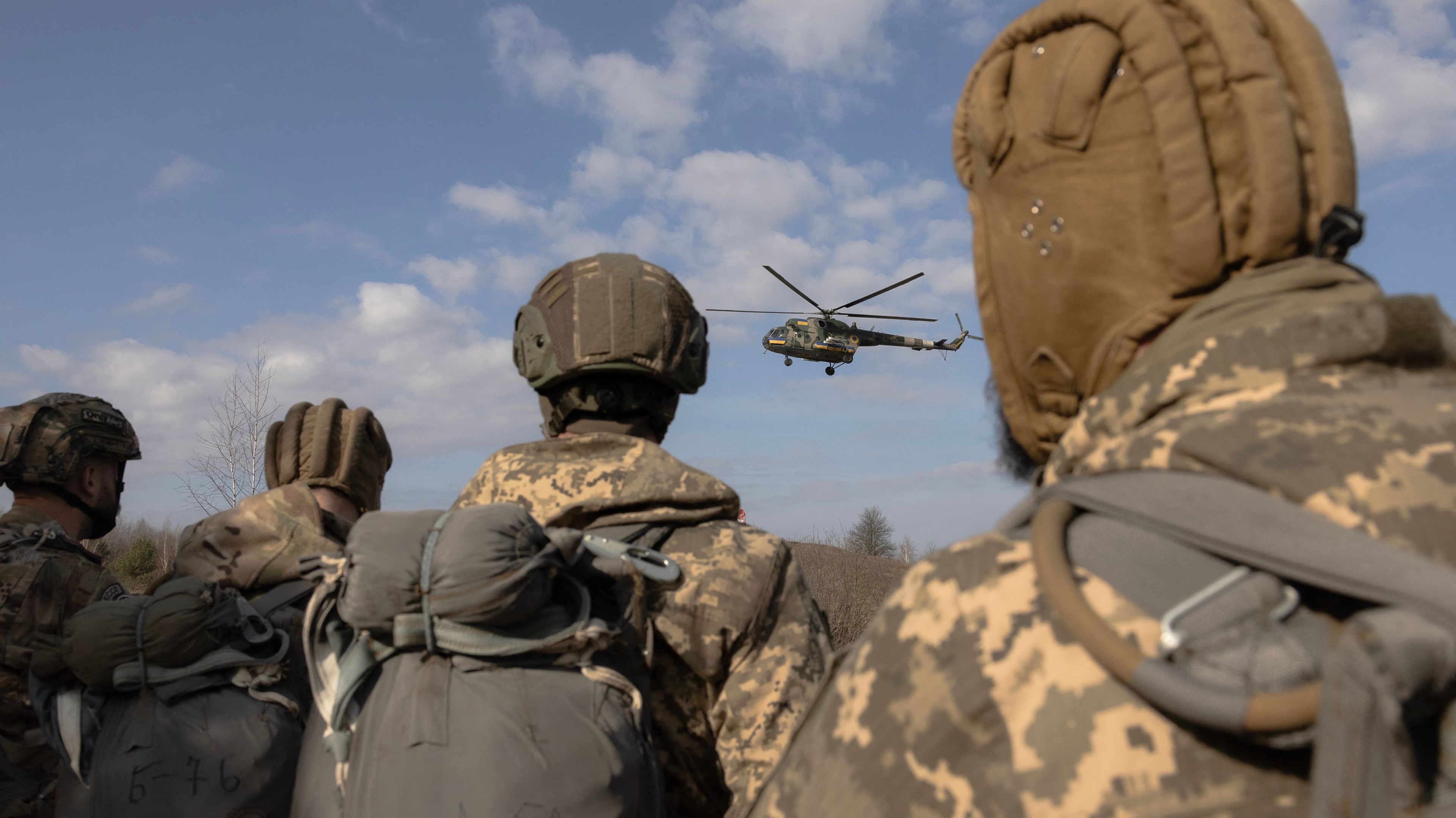 Żołnierze patrzą na lecący helikopter, ujecie zza pleców