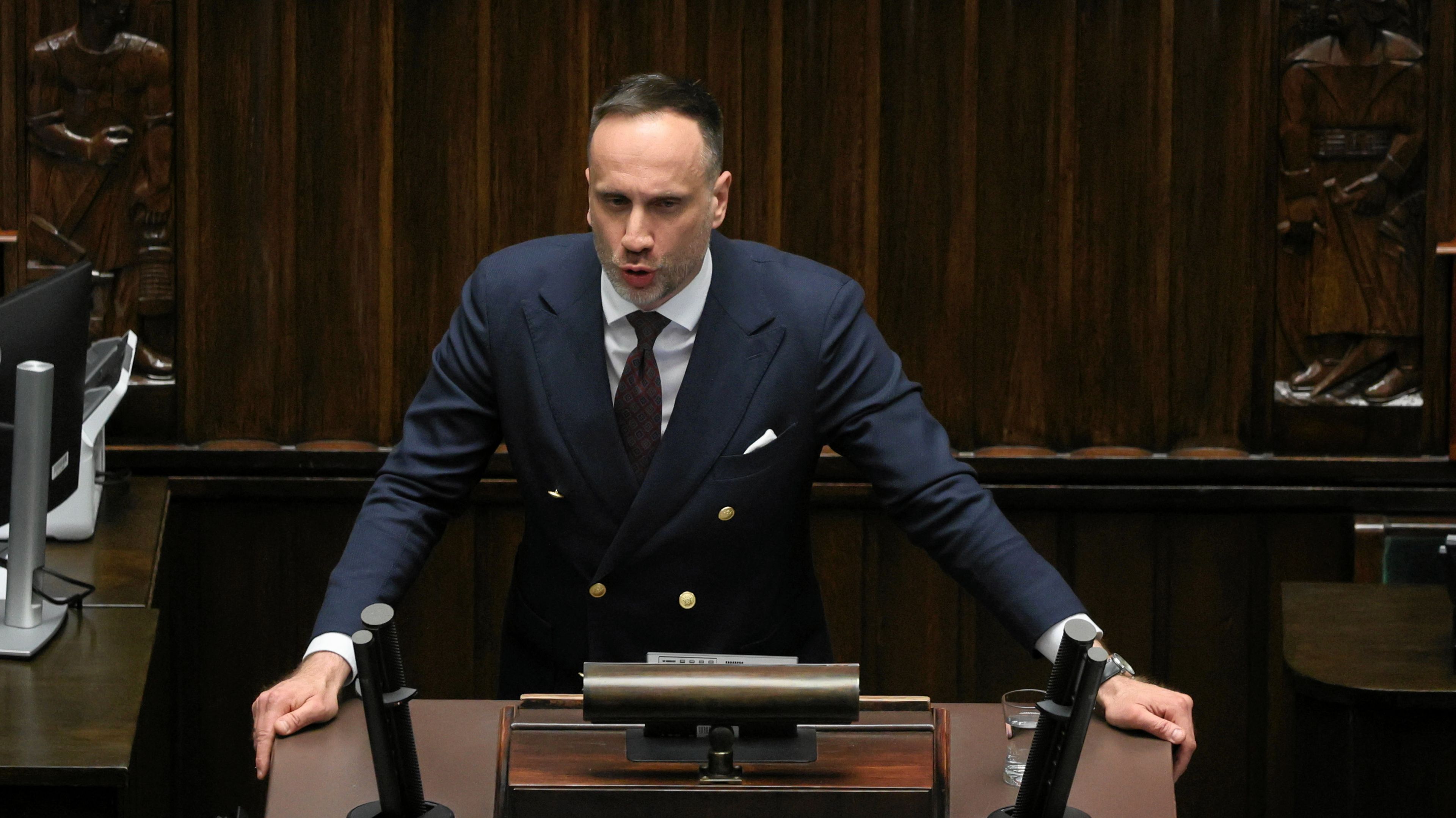 mężczyzna w garniturze na sejmowej mównicy