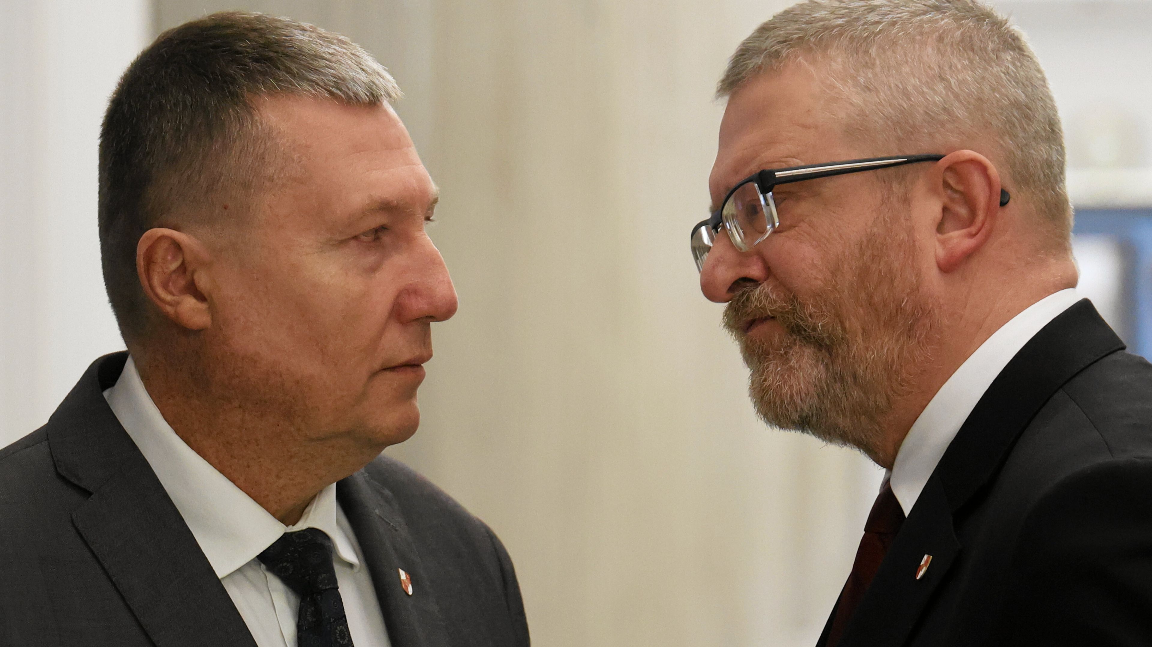 Dwaj mężczyźni stoją zwróceniu twarzami do siebie, jeden ma okulary i jest krótko ostrzyżony, drugi jest łysawy