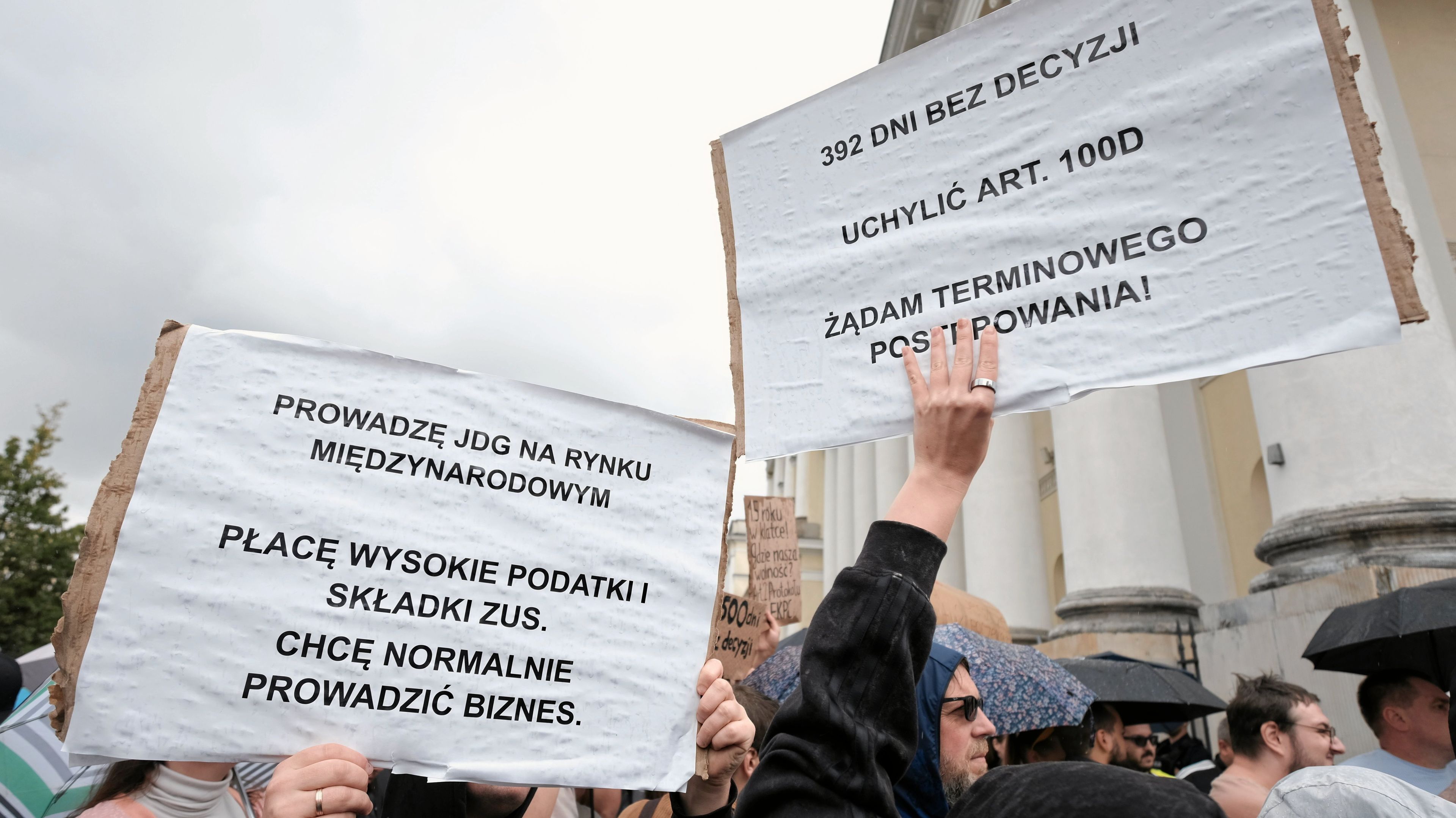Wzburzeni ludzie na ulicy trzymają w rękach plansze protestujące przeciw przewlekaniu spraw legalizacji w polskich urzędach