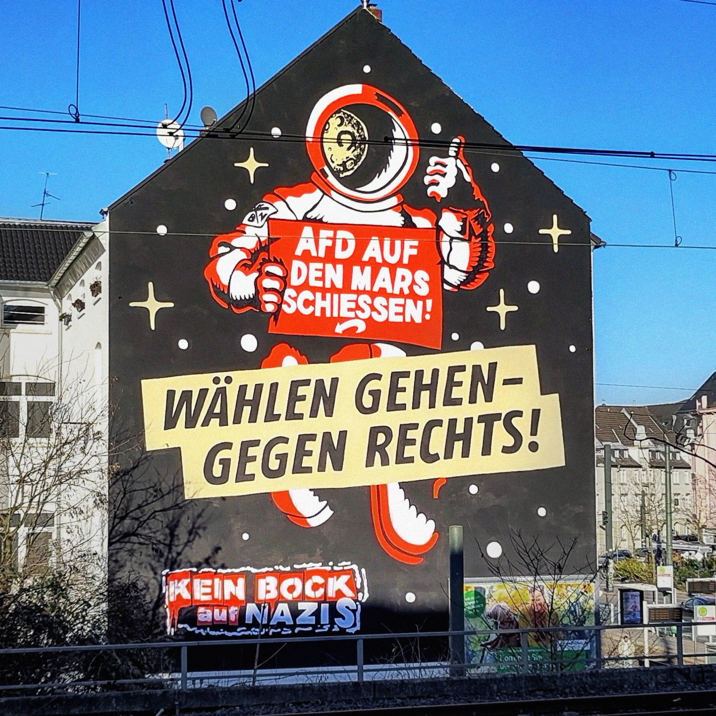 Mural z rysunkiem kosmonauty i hasłami w języku niemieckim