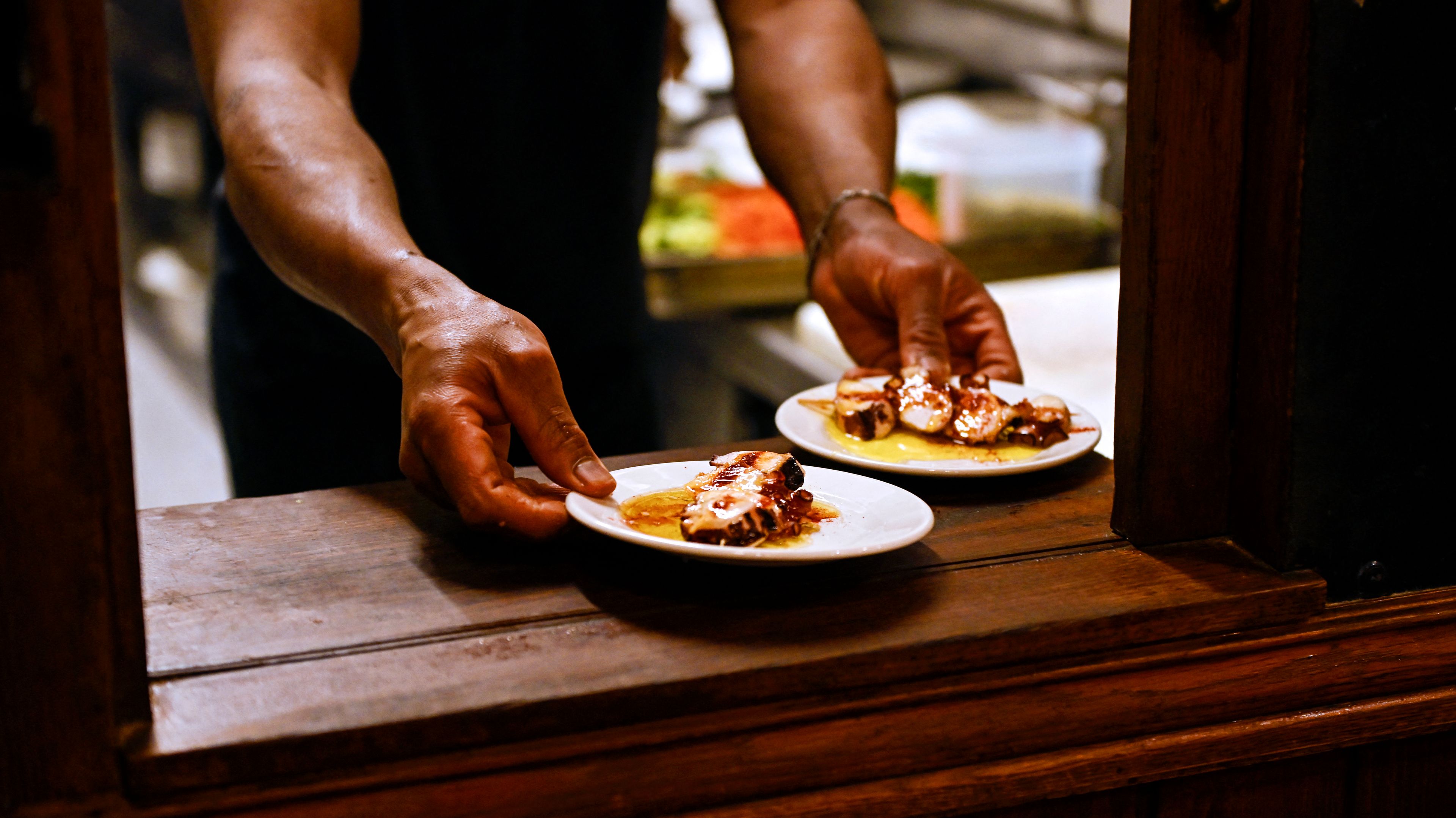 Ręce podające talerze z jedzeniem.