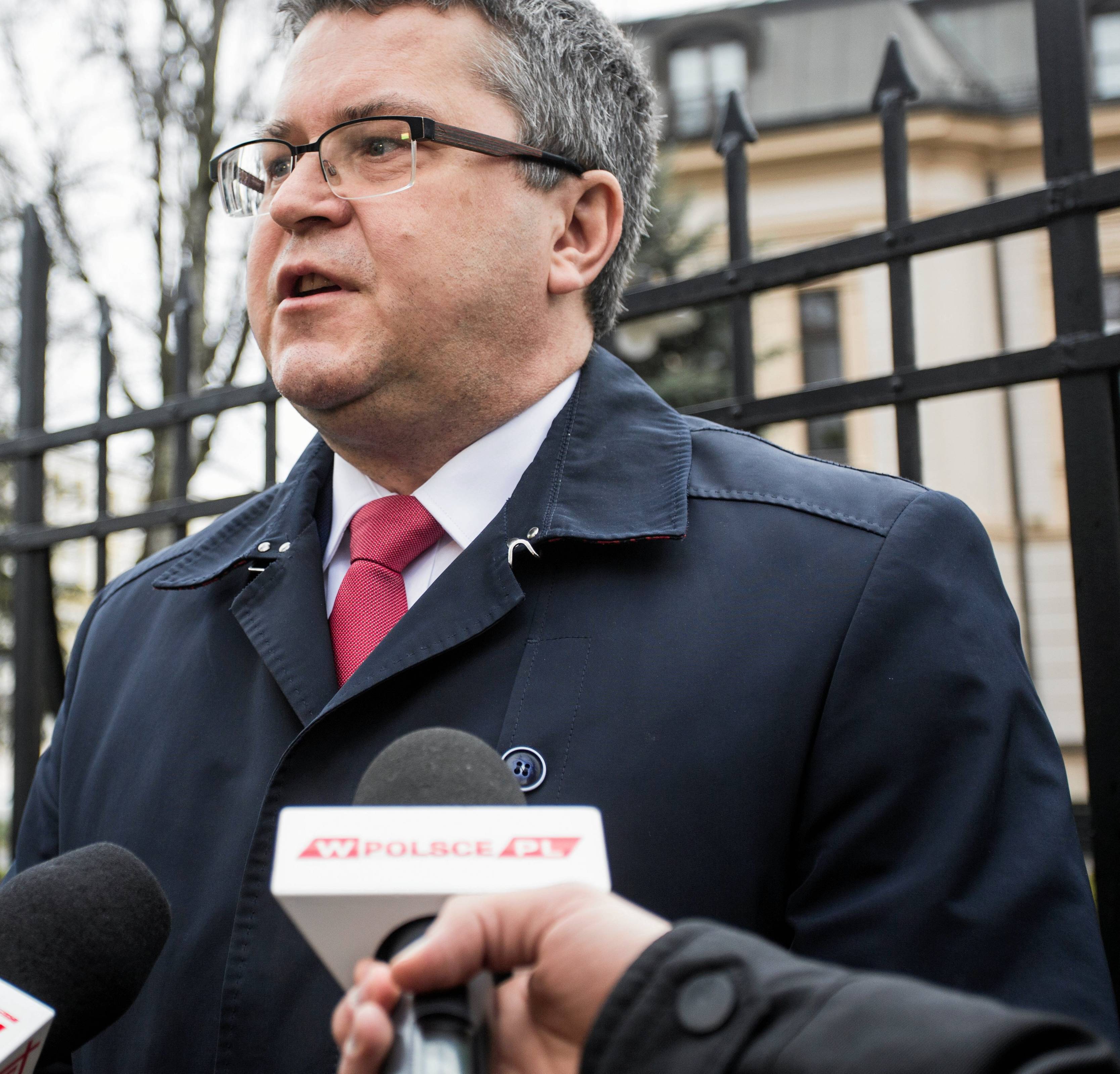 Mężczyzna w okularach stoi na tle metalowego płotu Trybunału Konstytucyjnego. Jarosław Dudzicz