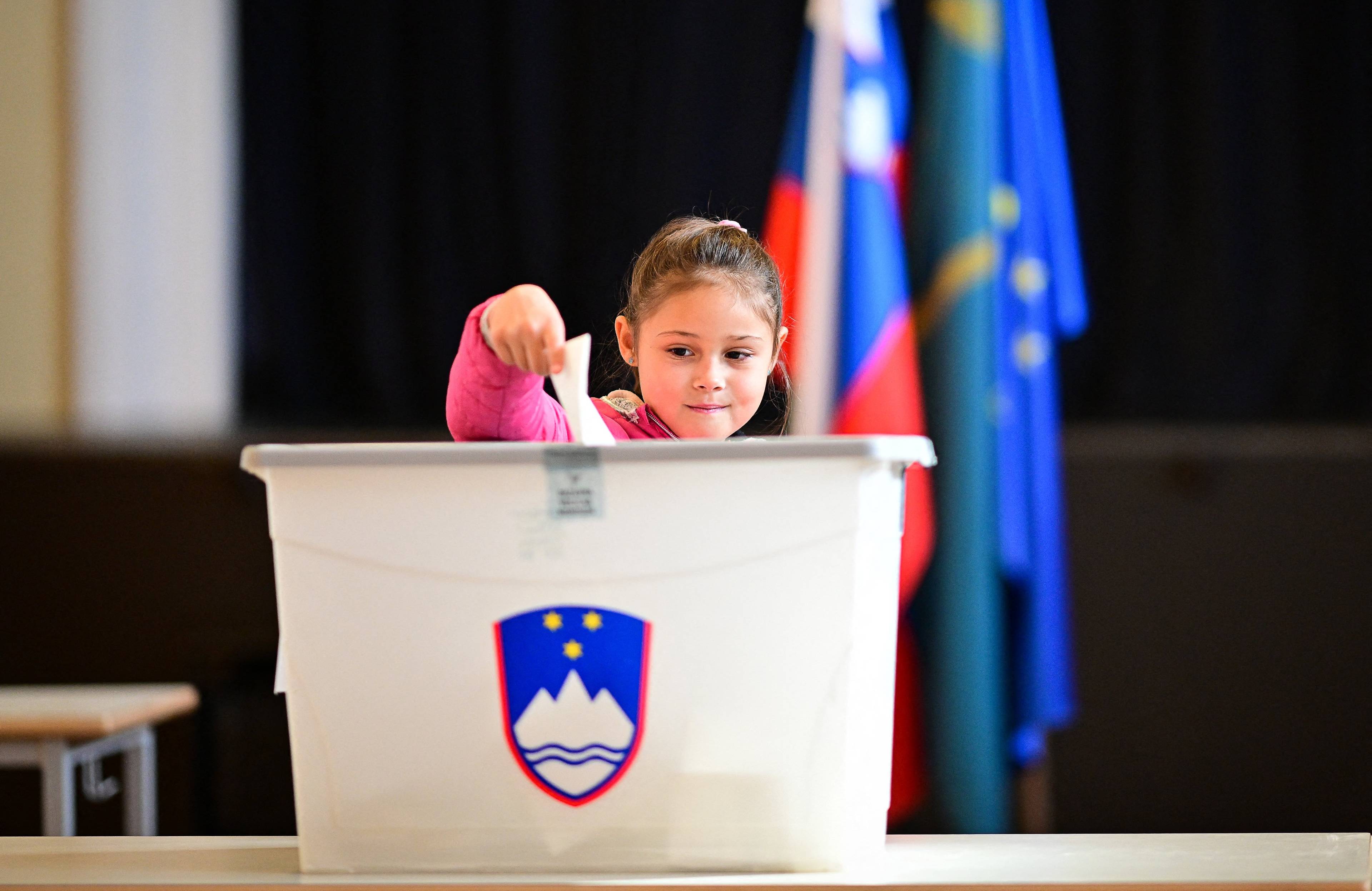 Młoda dziewczynka wrzuca głos do urny wyborczej podczas wyborów w Słowenii