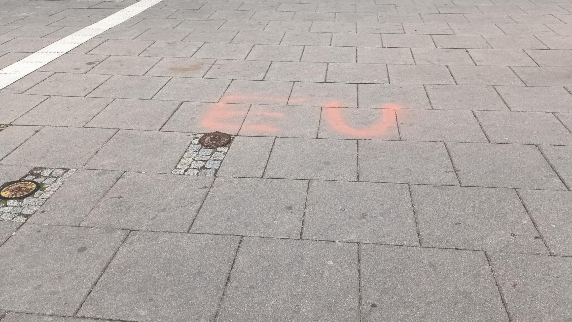 Czerwone litery "EU" słabo widoczne na chodniku