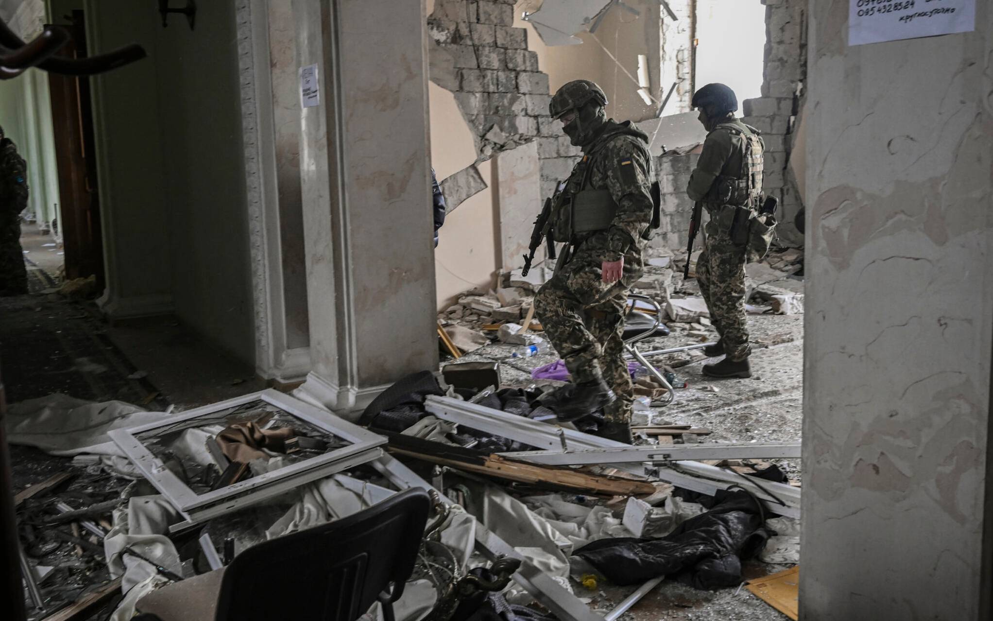 Ukranian servicemen walk inside the destroyed regional headquarters of Kharkiv on March 27, 2022. - France's President Emmanuel Macron has warned against a verbal "escalation" of Russia's invasion in Ukraine, after US President Joe Biden branded Vladimir Putin a "butcher" who "cannot remain in power".In Kharkiv, where authorities reported 44 artillery strikes and 140 rocket assaults in a single day, residents were resigned to the incessant bombardments. (Photo by Aris Messinis / AFP)