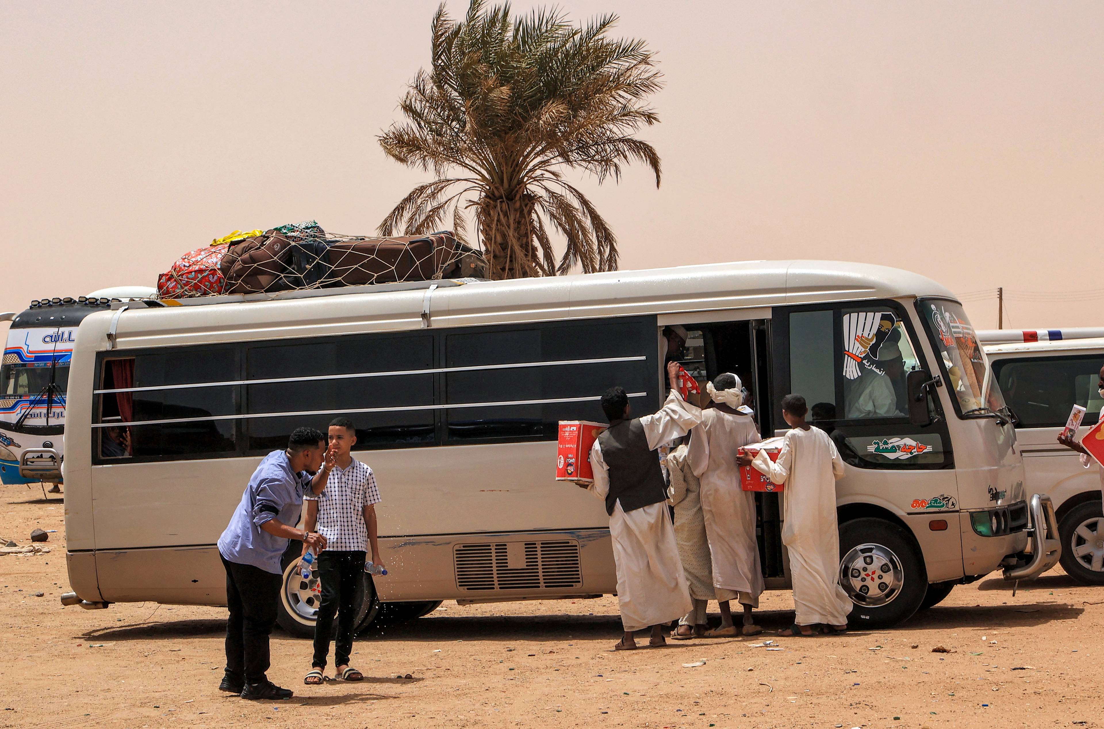Wewnętrzni uchodźcy w Sudanie. 25 kwietnia 2023 r. akwizytorzy oferują przekąski na sprzedaż ludziom wsiadającym do autobusu pasażerskiego na przystanku Multaga w pobliżu Ganetti w północnym stanie Sudanu, około 300 kilometrów na północny zachód od stolicy