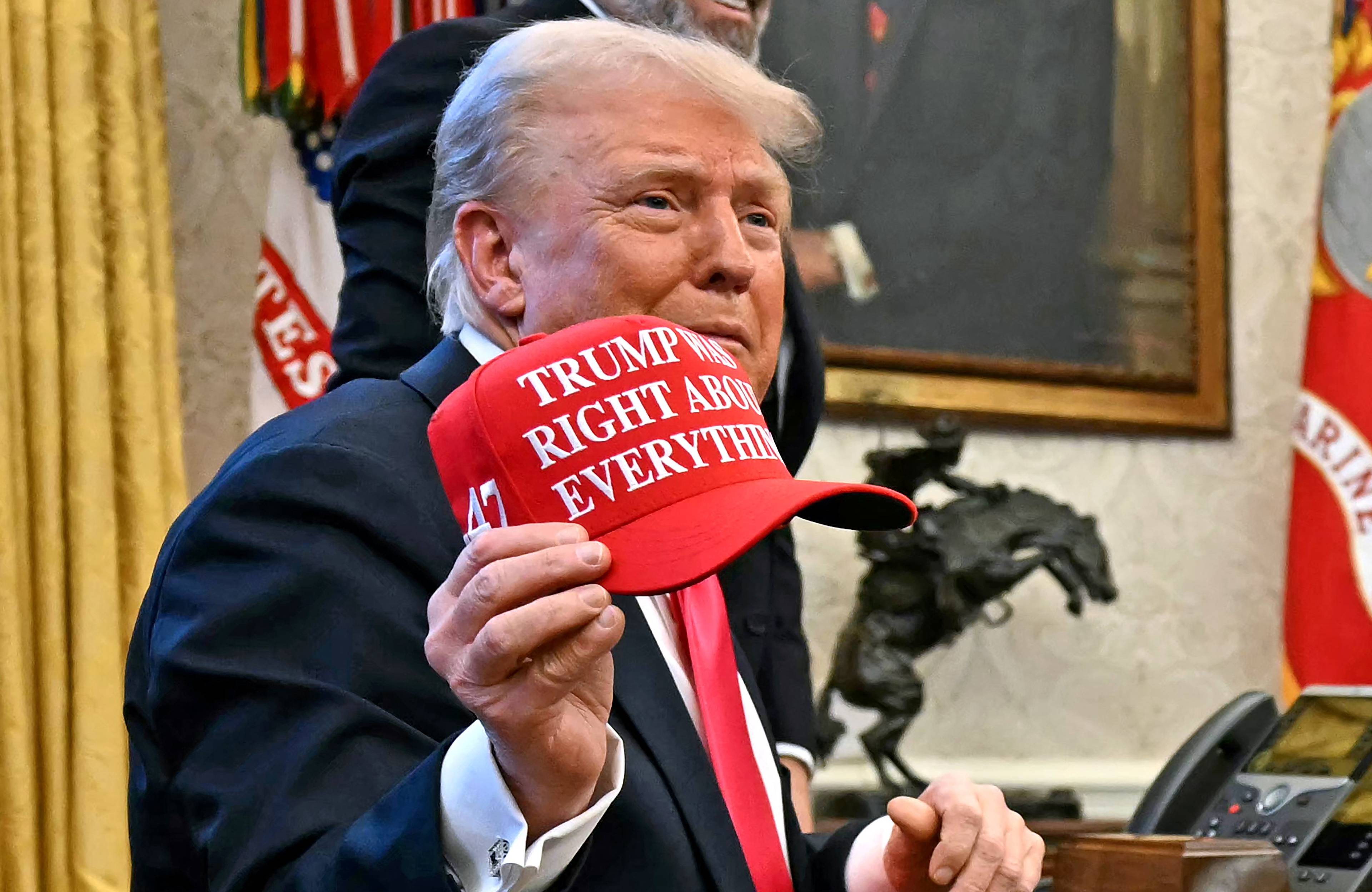 Trump trzyma czerwoną czapkę z napisem "Trump was right about everything"