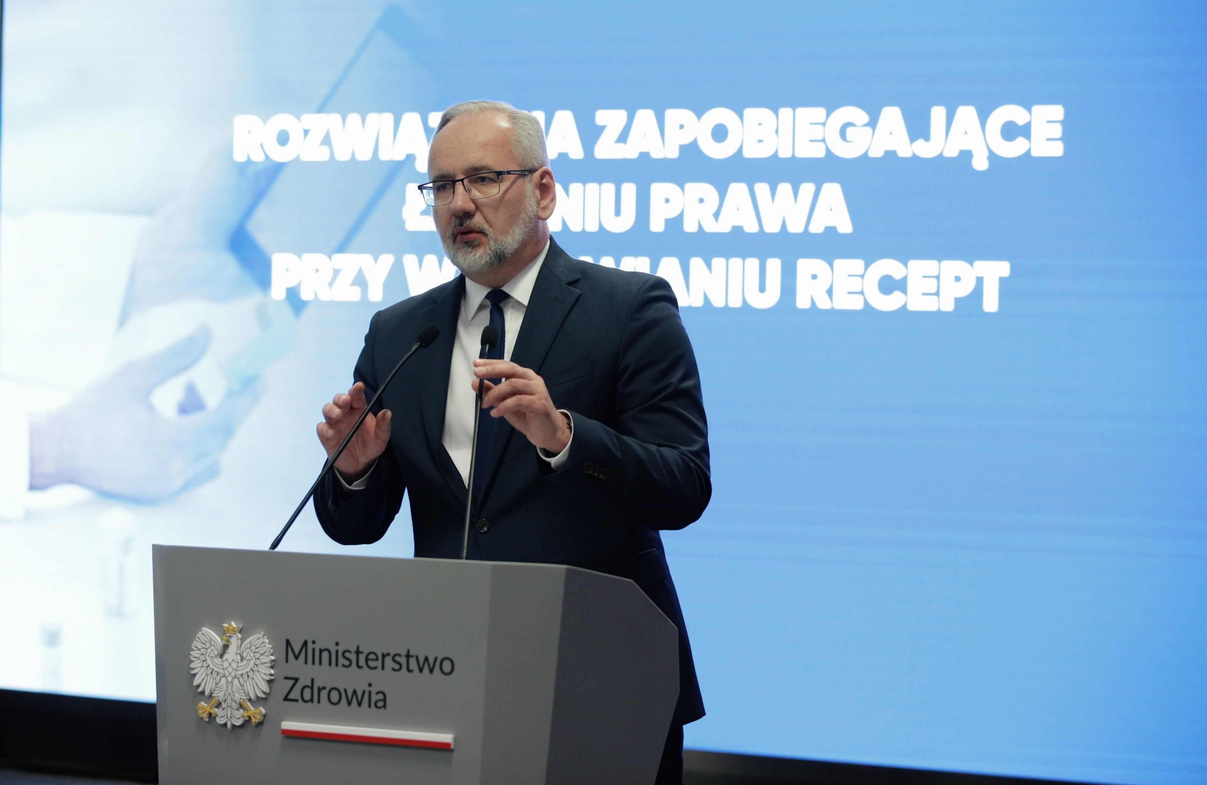 30.06.2023, Warszawa. Adam Niedzielski przemawia na mównicy podczas konferencji prasowej w Ministerstwie Zdrowia. Za nim na ekranie wyświetla się napis "Rozwiązania zapobiegające łamaniu prawa przy wystawianiu recept"