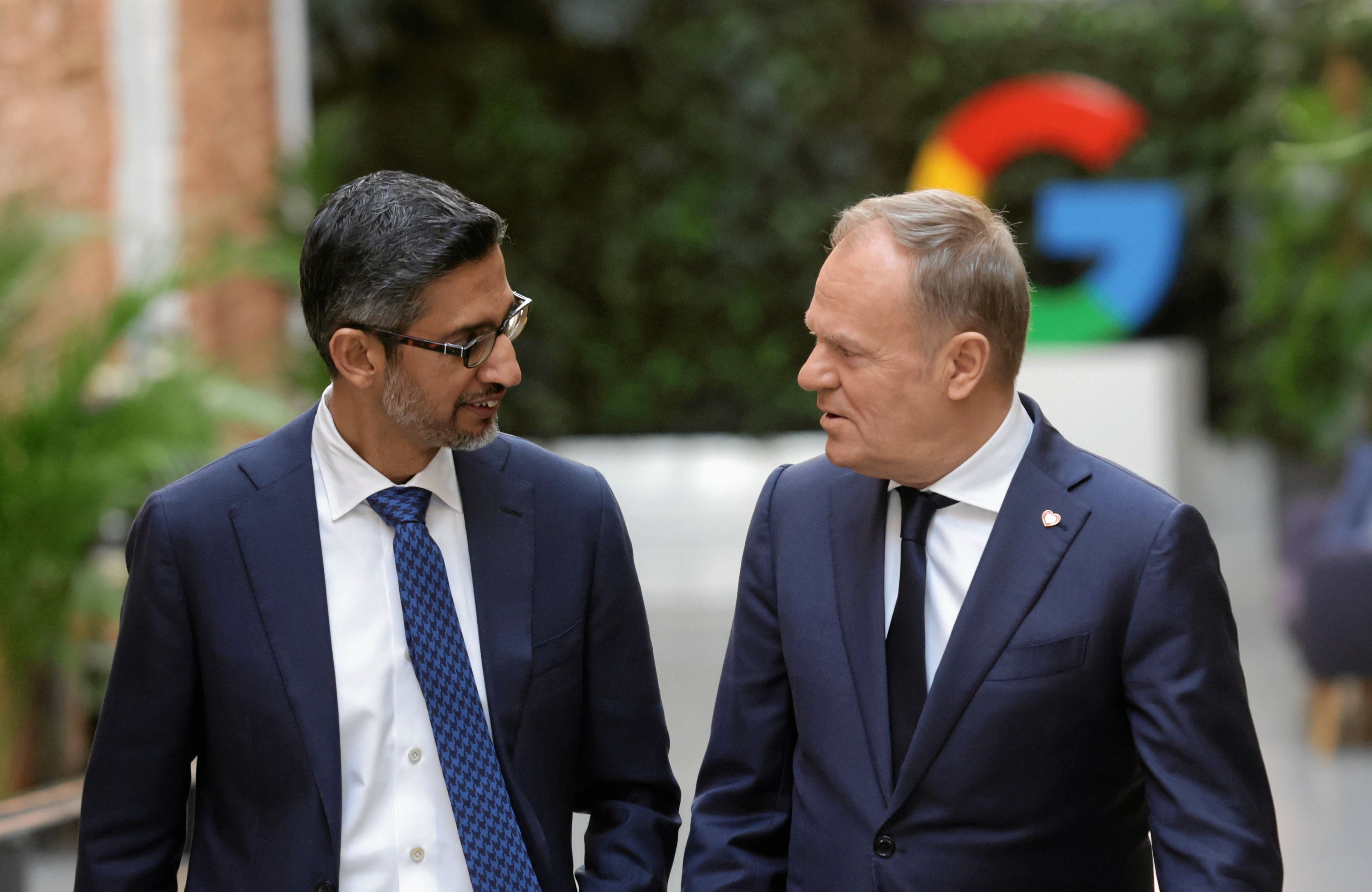 Tusk i Sundar Pichai idą uliczką, w tle duże G, logo firmy google