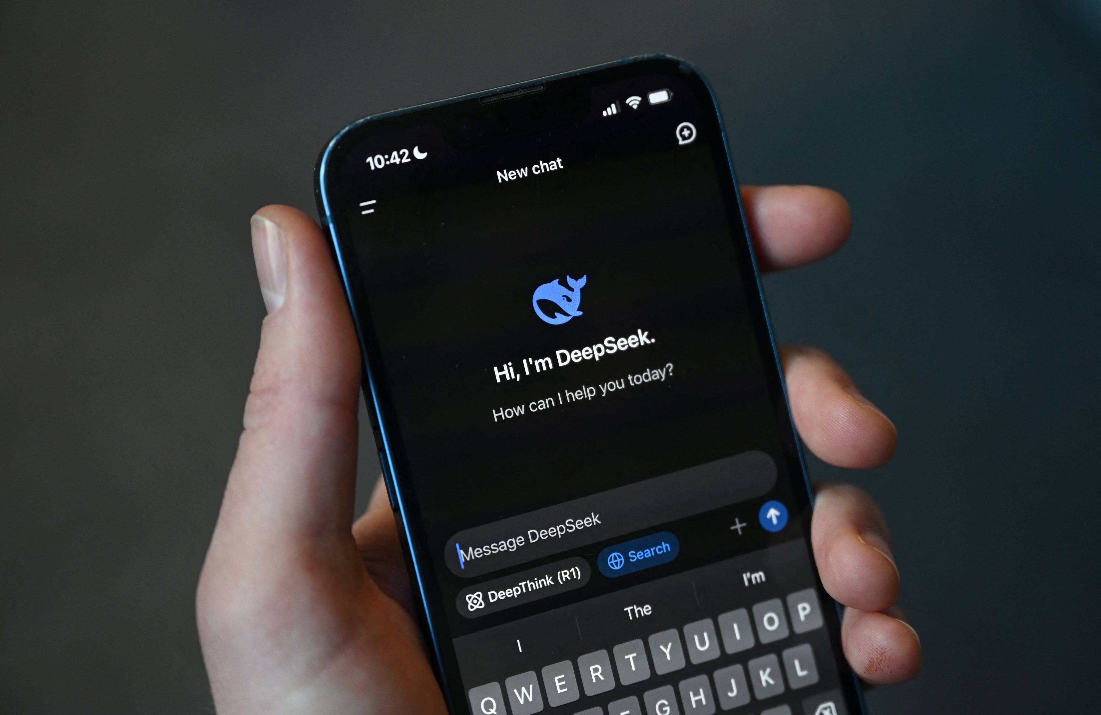 Dłoń trzymająca telefon. Pokazuje napis: „Hi, I'm DeepSeek”