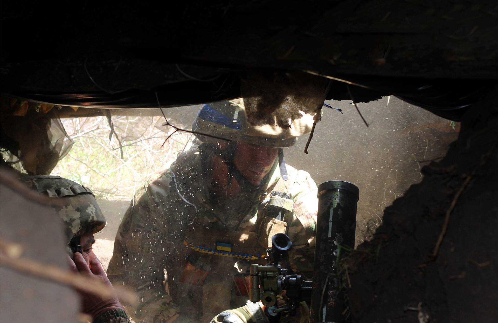 na zdjęciu dwóch żołnierzy w polowych mundurach ładuje moździerz ukryty w okopie. Konstantynówka, Ukraina