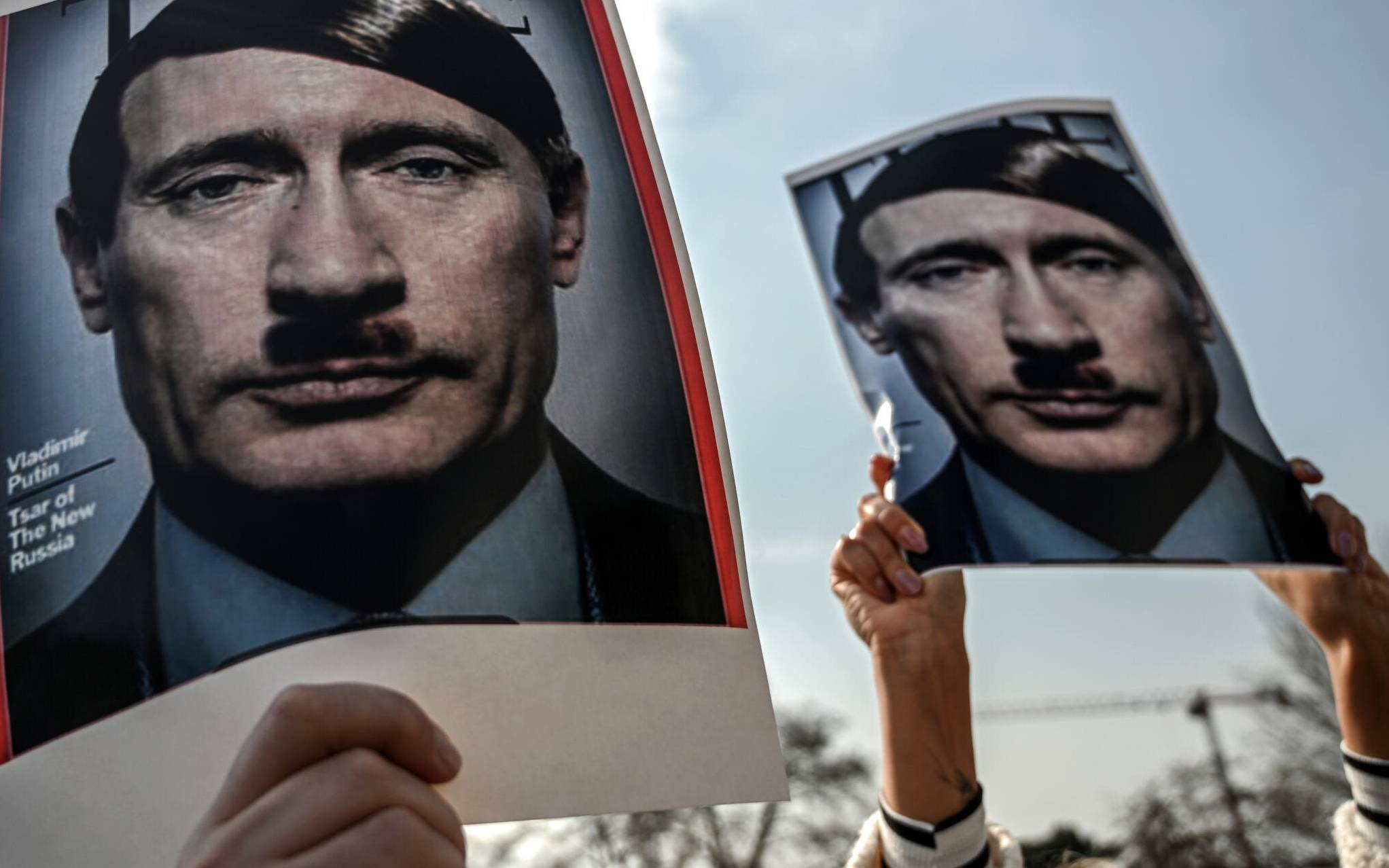 Protesters hold pictures depicting Russian President Vladimir Putin as Adolf Hitler during a rally against Russia's invasion of Ukraine at Beyazid district in Istanbul, on February 26, 2022. (Photo by Ozan KOSE / AFP)