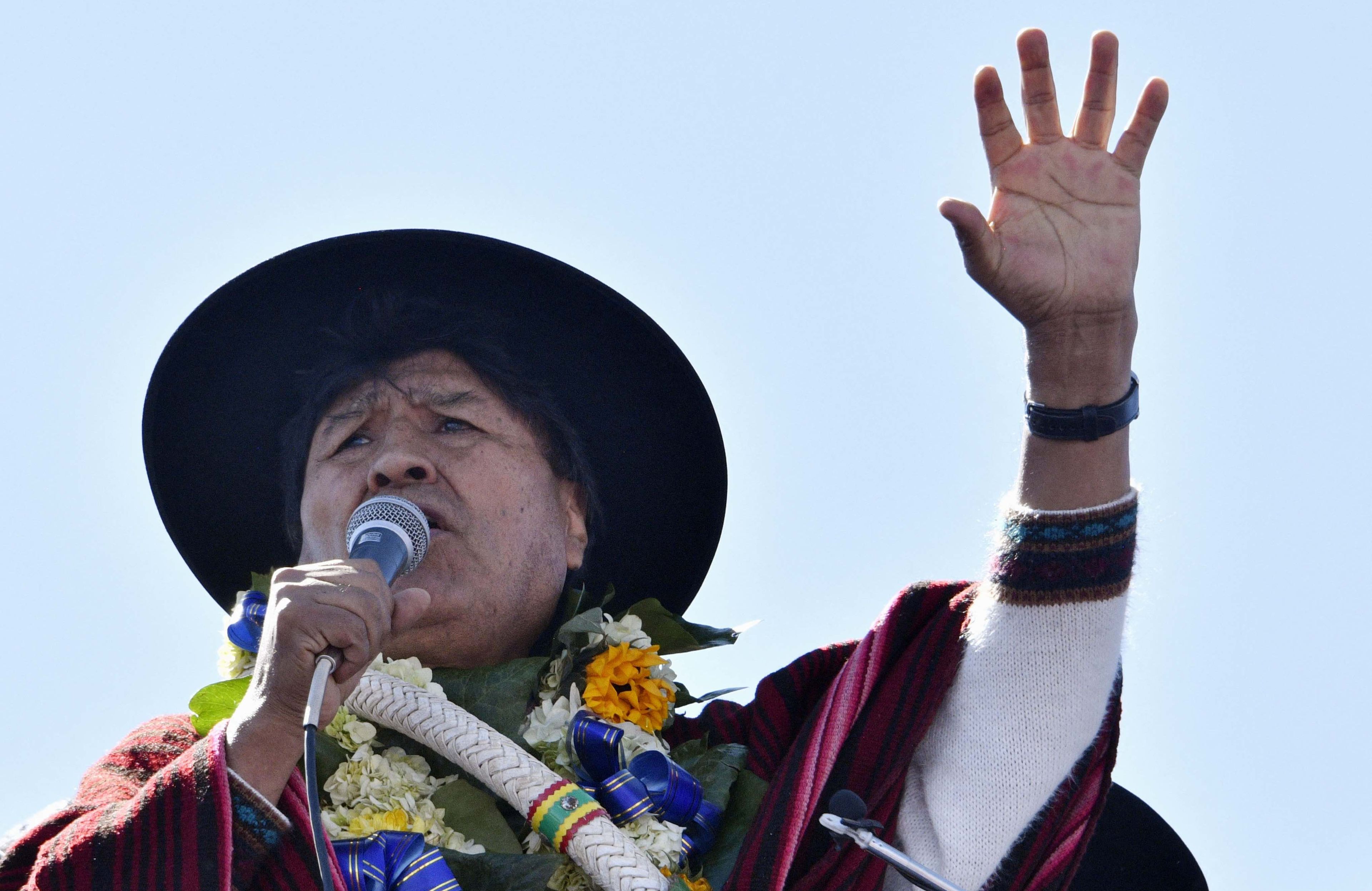 Evo Morales w kapeluszu pozdrawia swoich wyborców na wiecu, podnosząc rękę