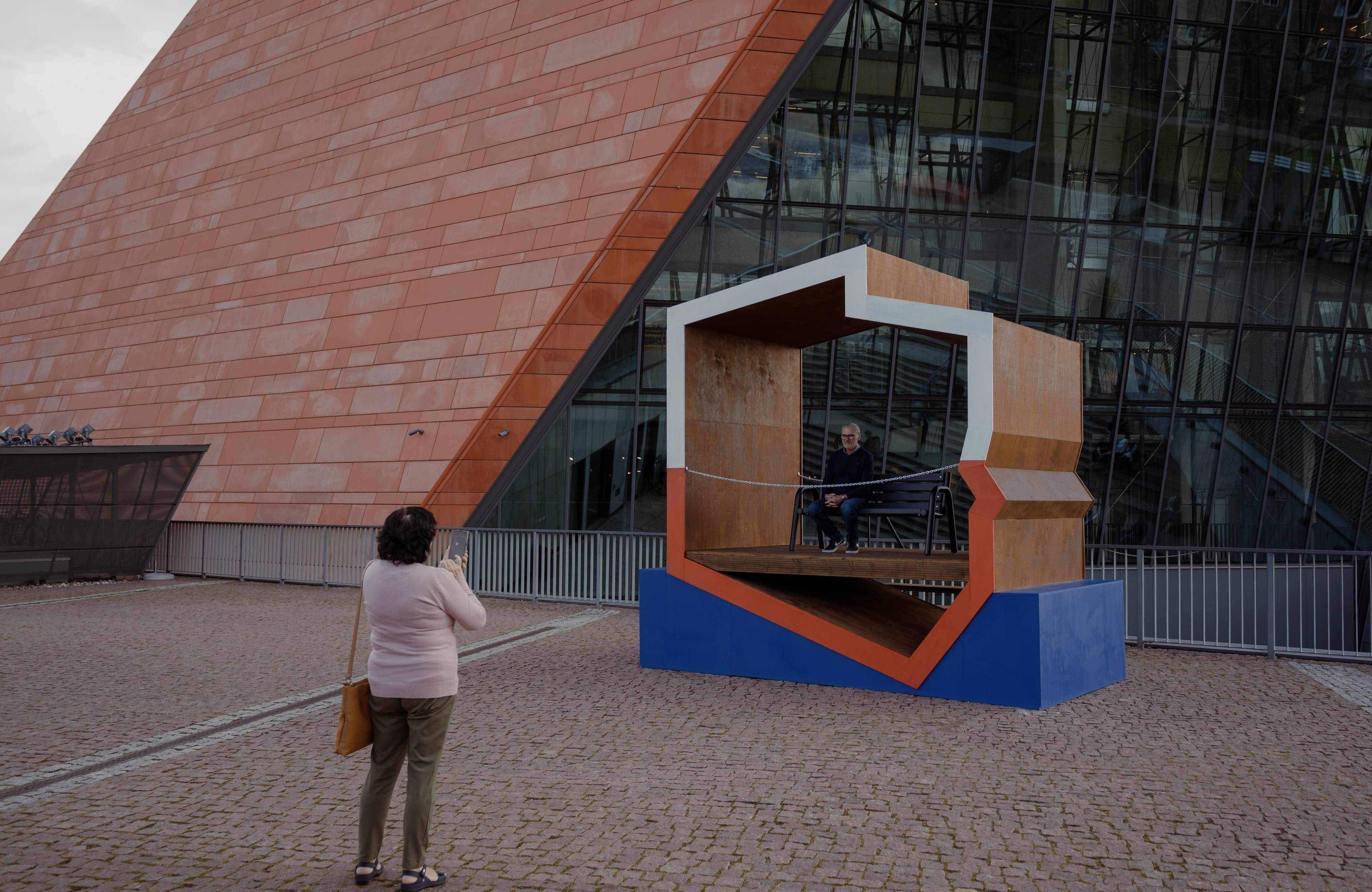 Na zdjęciu widać kobietę, która rozbi zdjęcie budynku Muzeum II Wojny Światowej w Gdańsku.