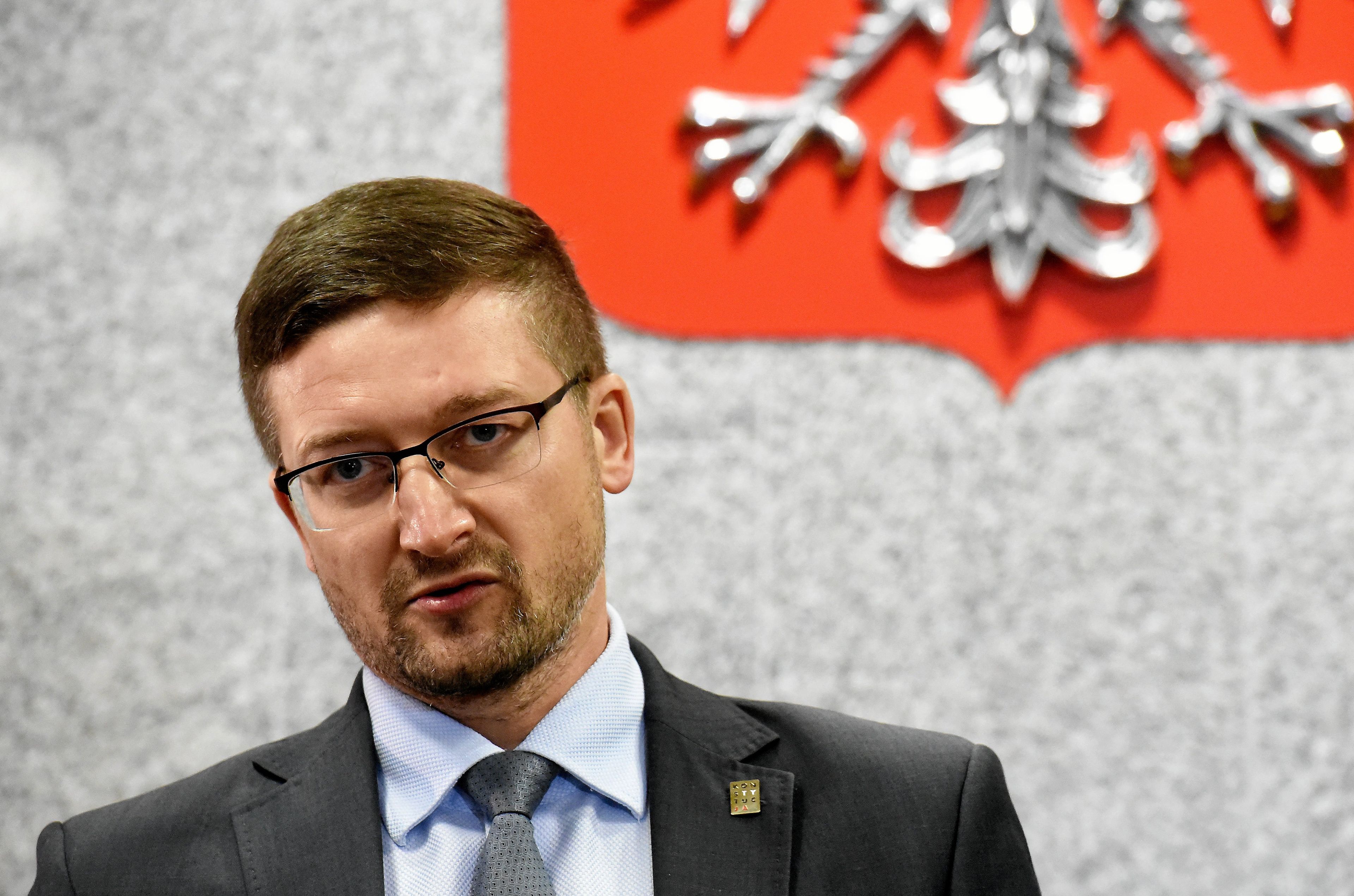 Sędzia Paweł Juszczyszyn stoi na tle polskiego godła
