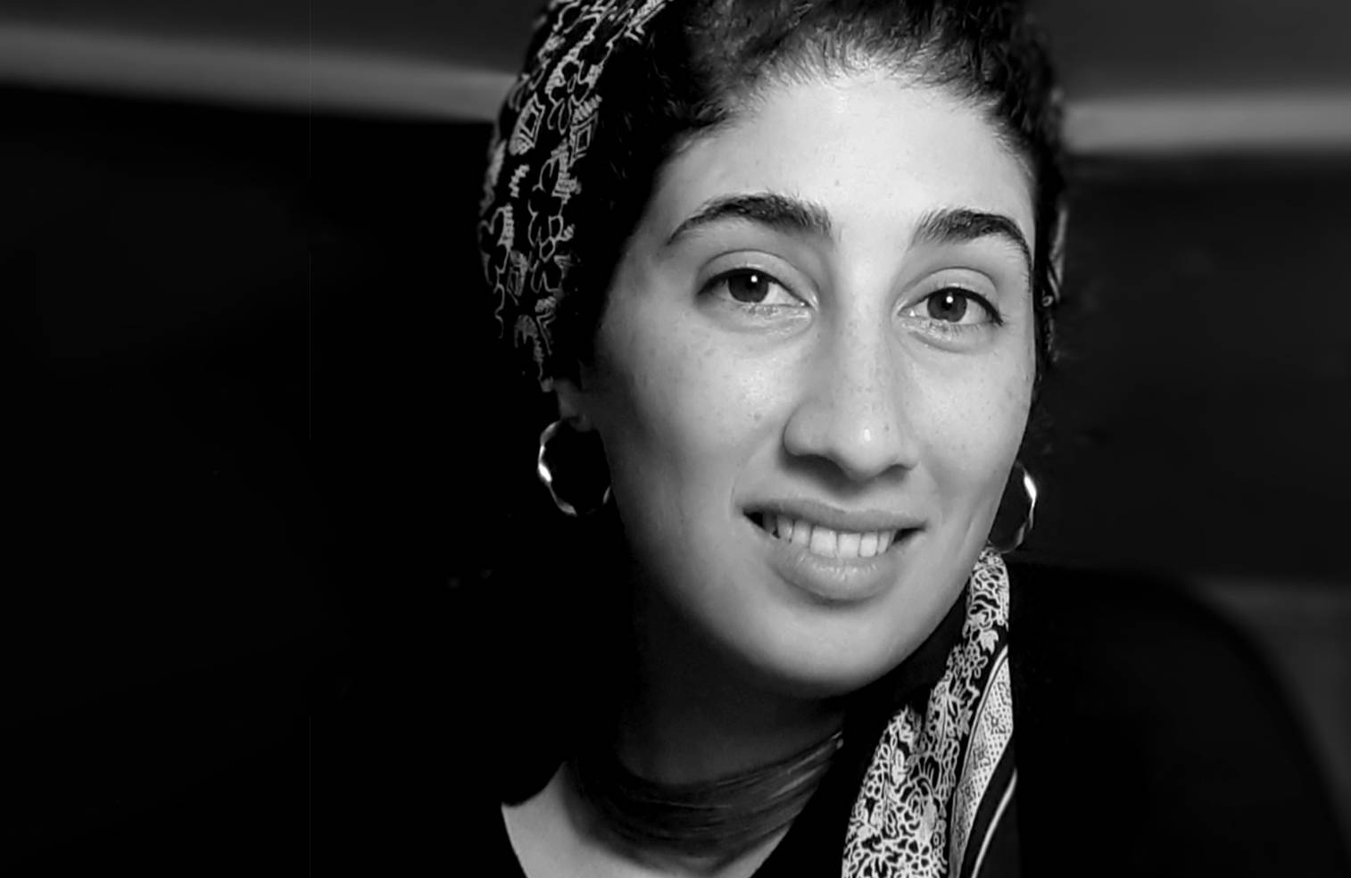 Zdjęcie Sarwat, syryjskiej poetki i feministki – lekko uśmiechnięta kobieta w chuście i kolczykach