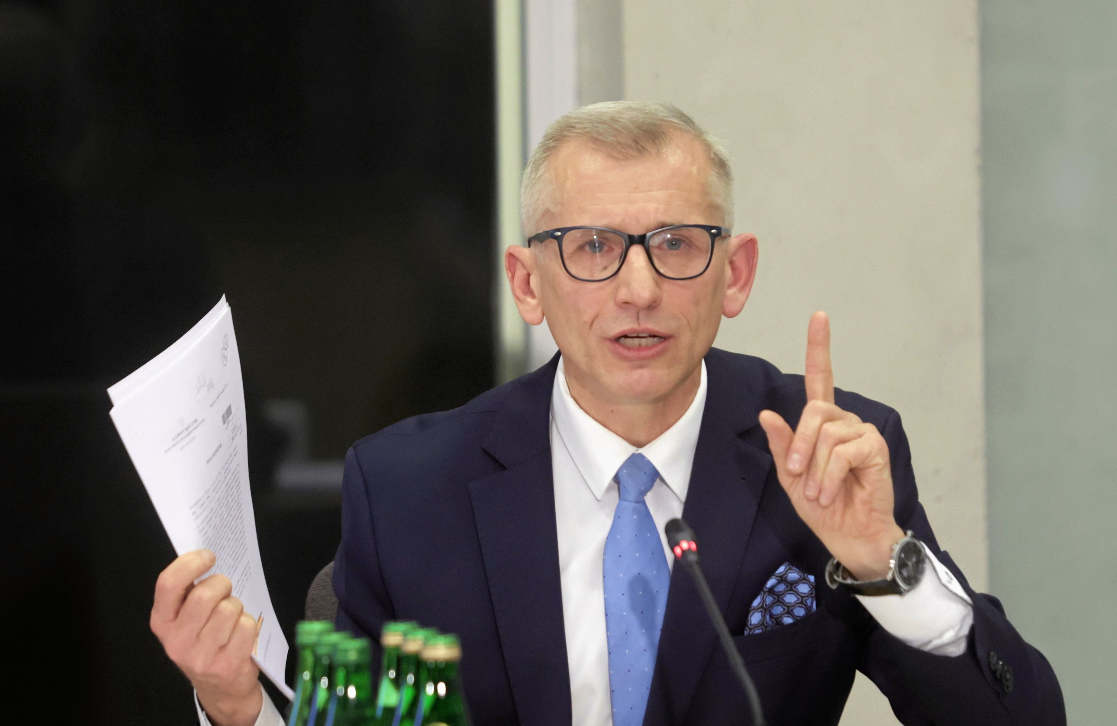 Krzysztof Kwiatkowski pokazuje dokumenty i podnosi palec wskazujący