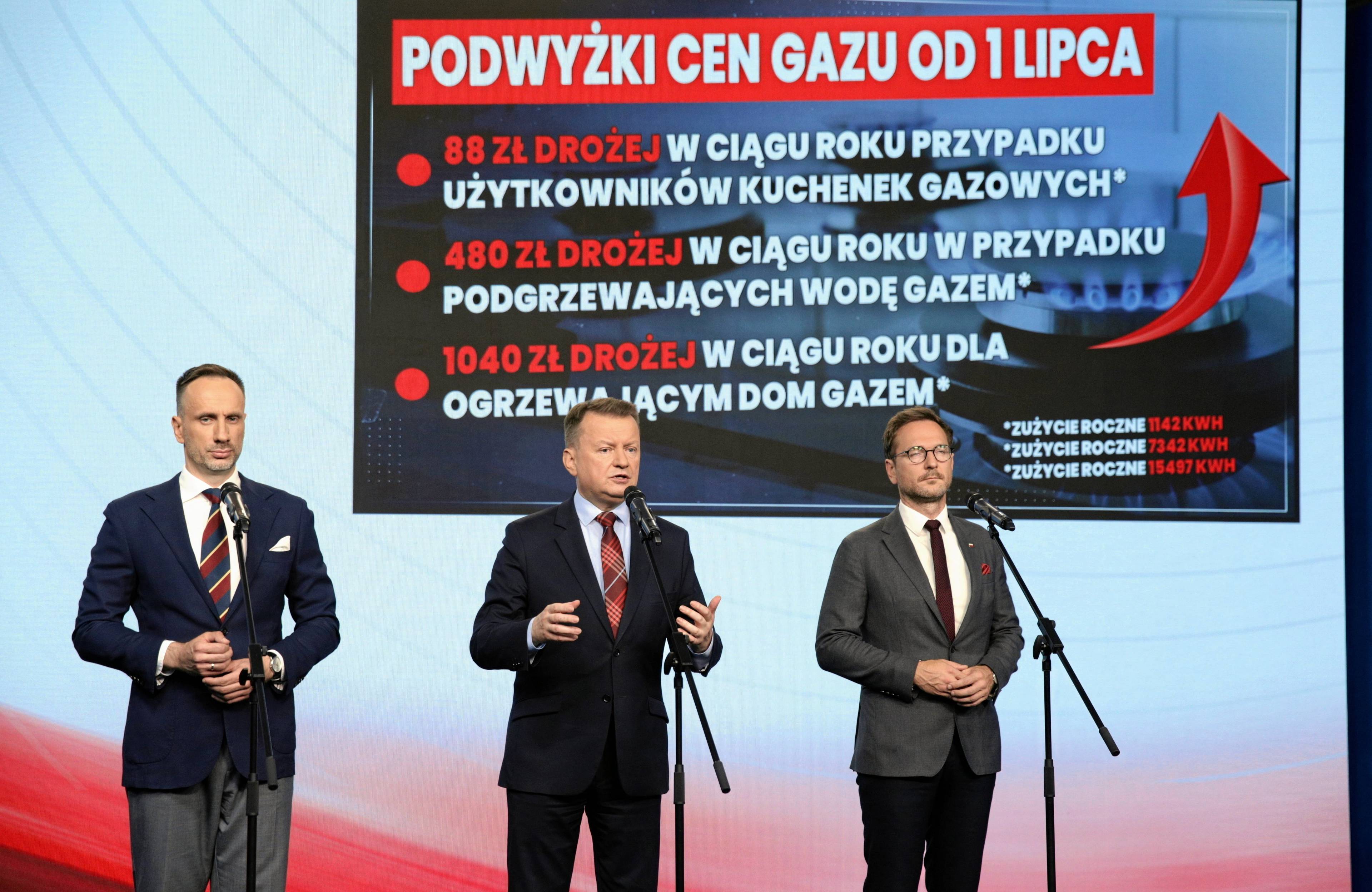 Trzech polityków PiS na konferencji prasowej na tle planszy z napisem "PODWYŻKI CEN GAZU OD 1 LIPCA"