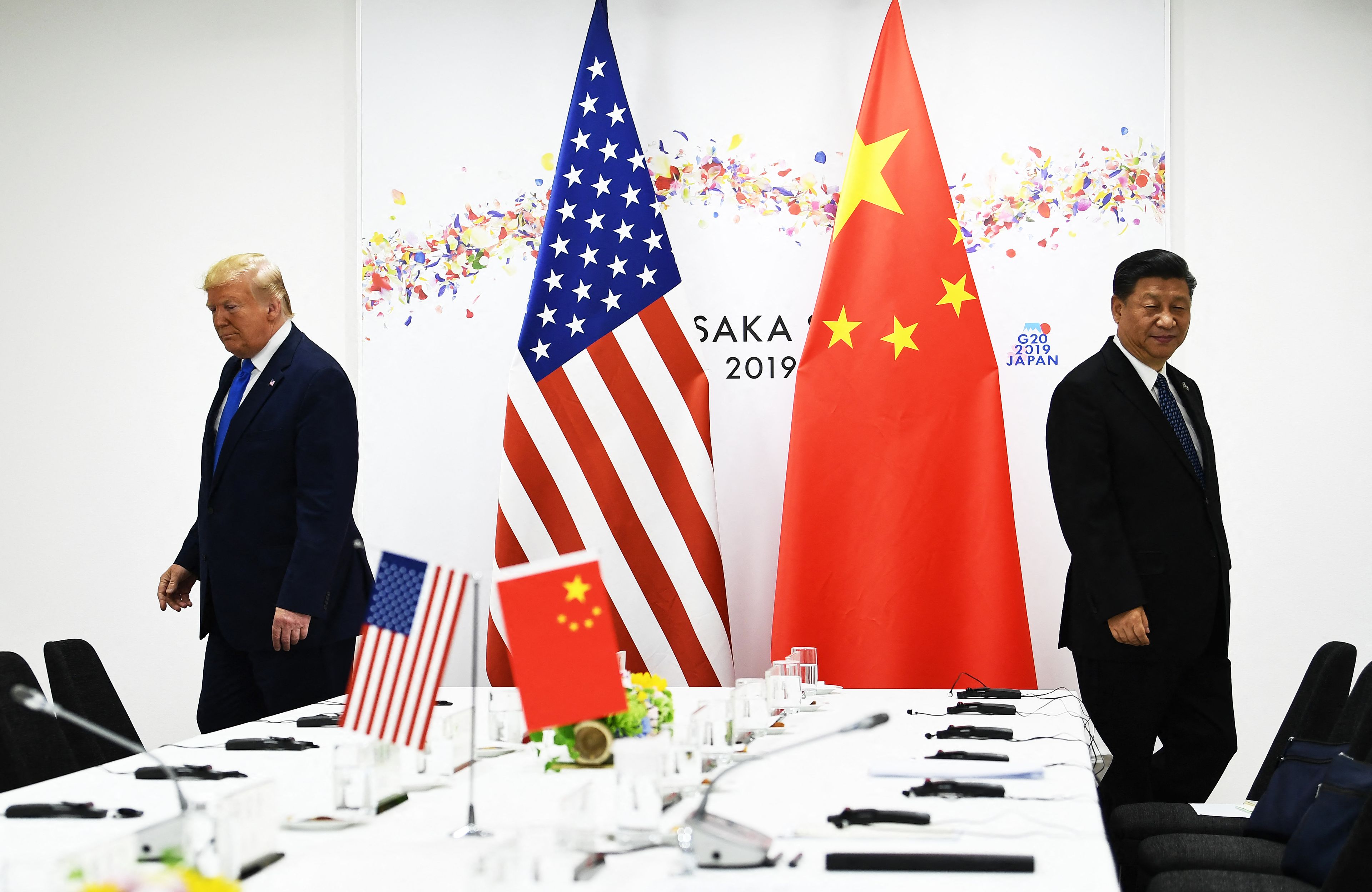 Donald Trump i Xi Jinping przy flagach amerykańskiej i chińskiej przy długim stole
