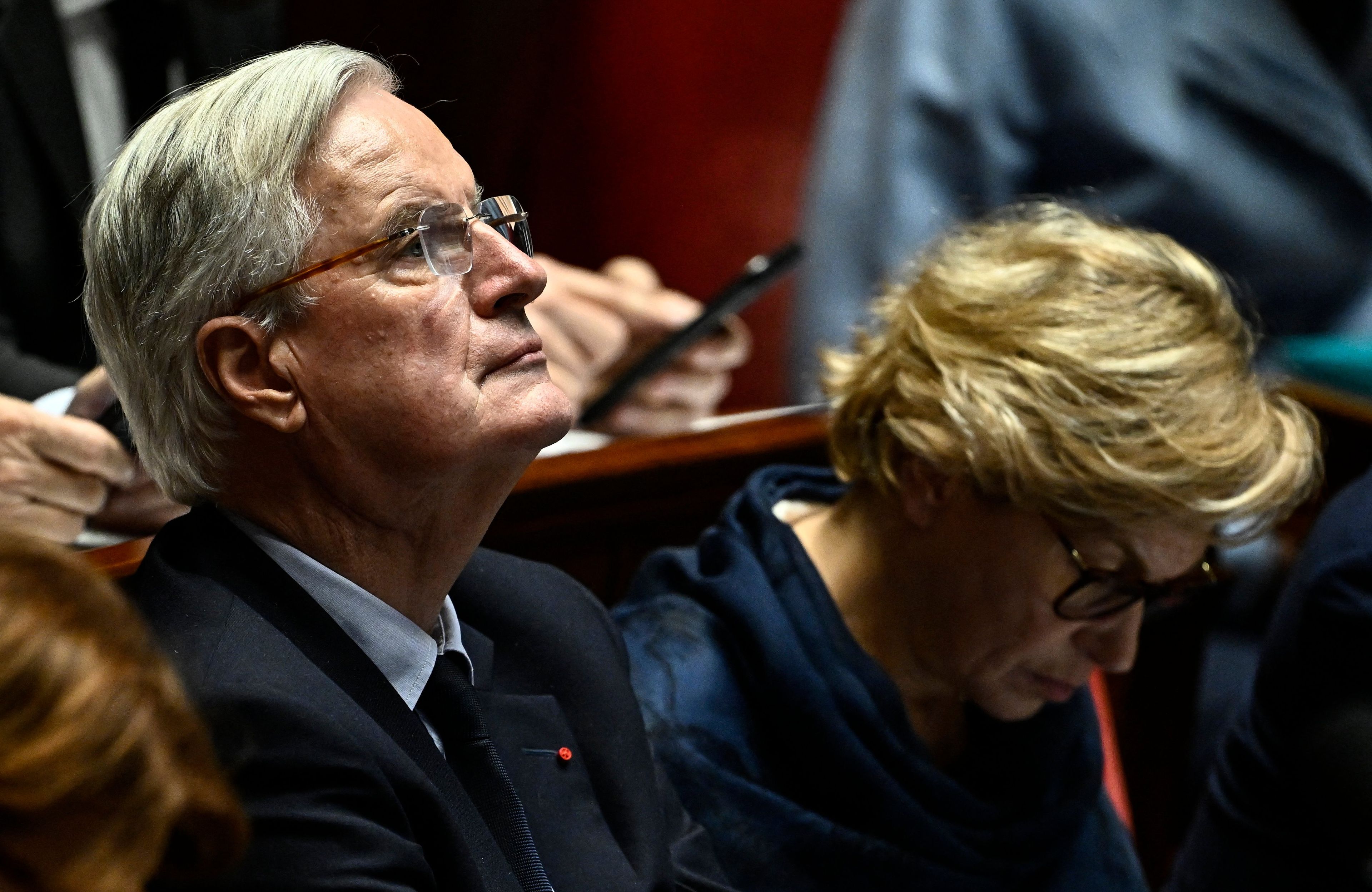Barnier patrzy przed siebie, w okularach, z profilu
