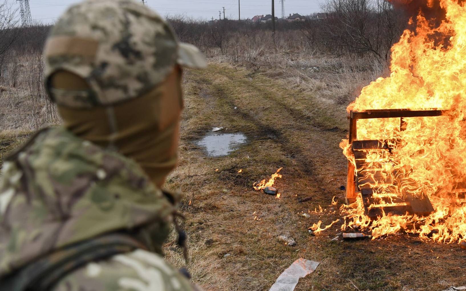 A Ukrainian soldier looks at flames after throwing a cocktail Molotovs during a self-defence civilian course on the outskirts of Lviv, western Ukraine, on March 4, 2022. - The Russian army occupied on March 4, 2022 the Ukrainian nuclear power plant of Zaporozhie (south), the largest in Europe, where bombings in the night have raised fears of a disaster as more than 1.2 million people have fled Ukraine into neighbouring countries since Russia launched its full-scale invasion on February 24, United Nations figures showed on March 4, 2022. (Photo by Daniel LEAL / AFP)