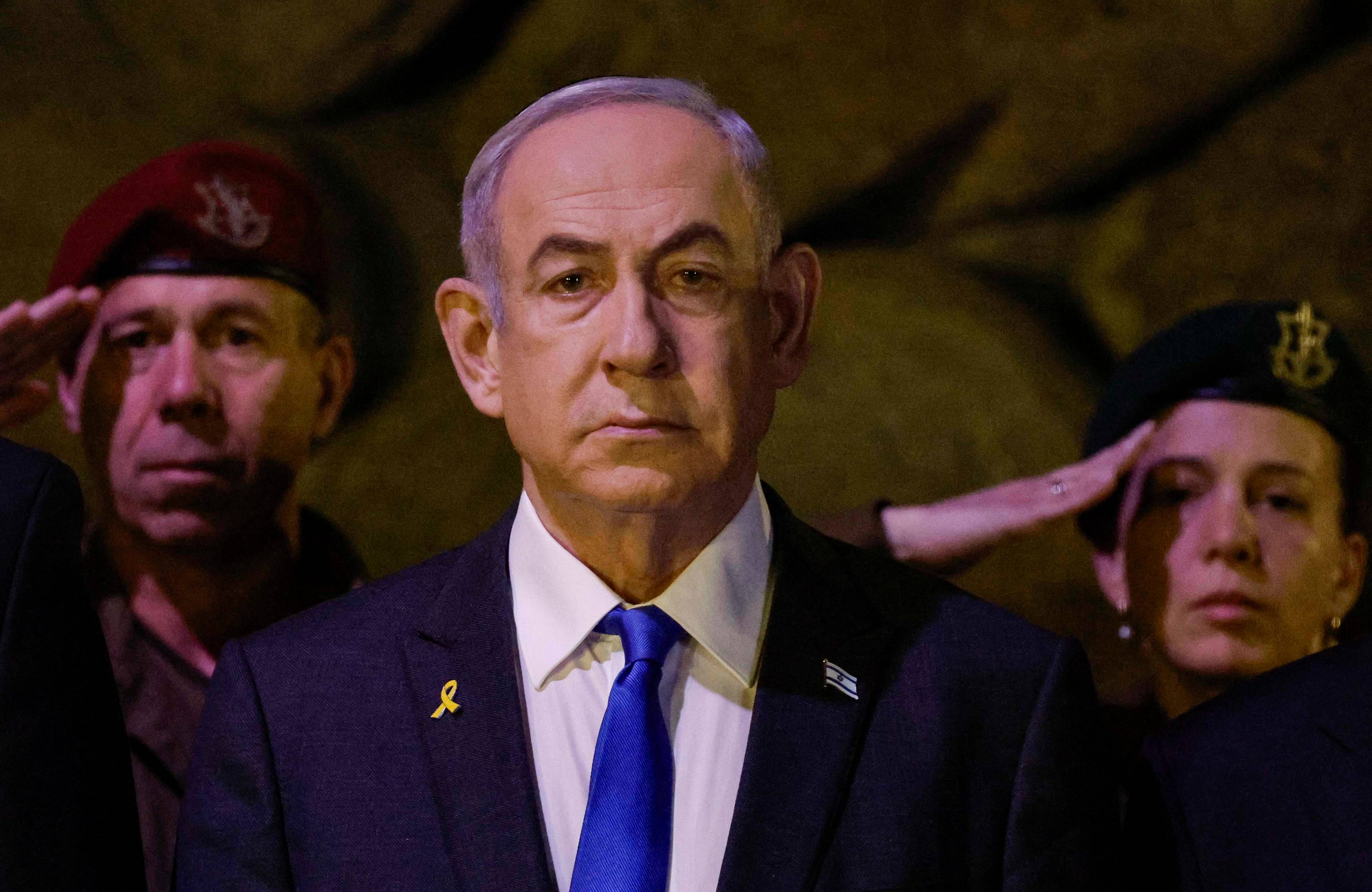 Binjamin Netanjahu, po jego prawej i lewej stronie żołnierz i żołnierka którzy salutują