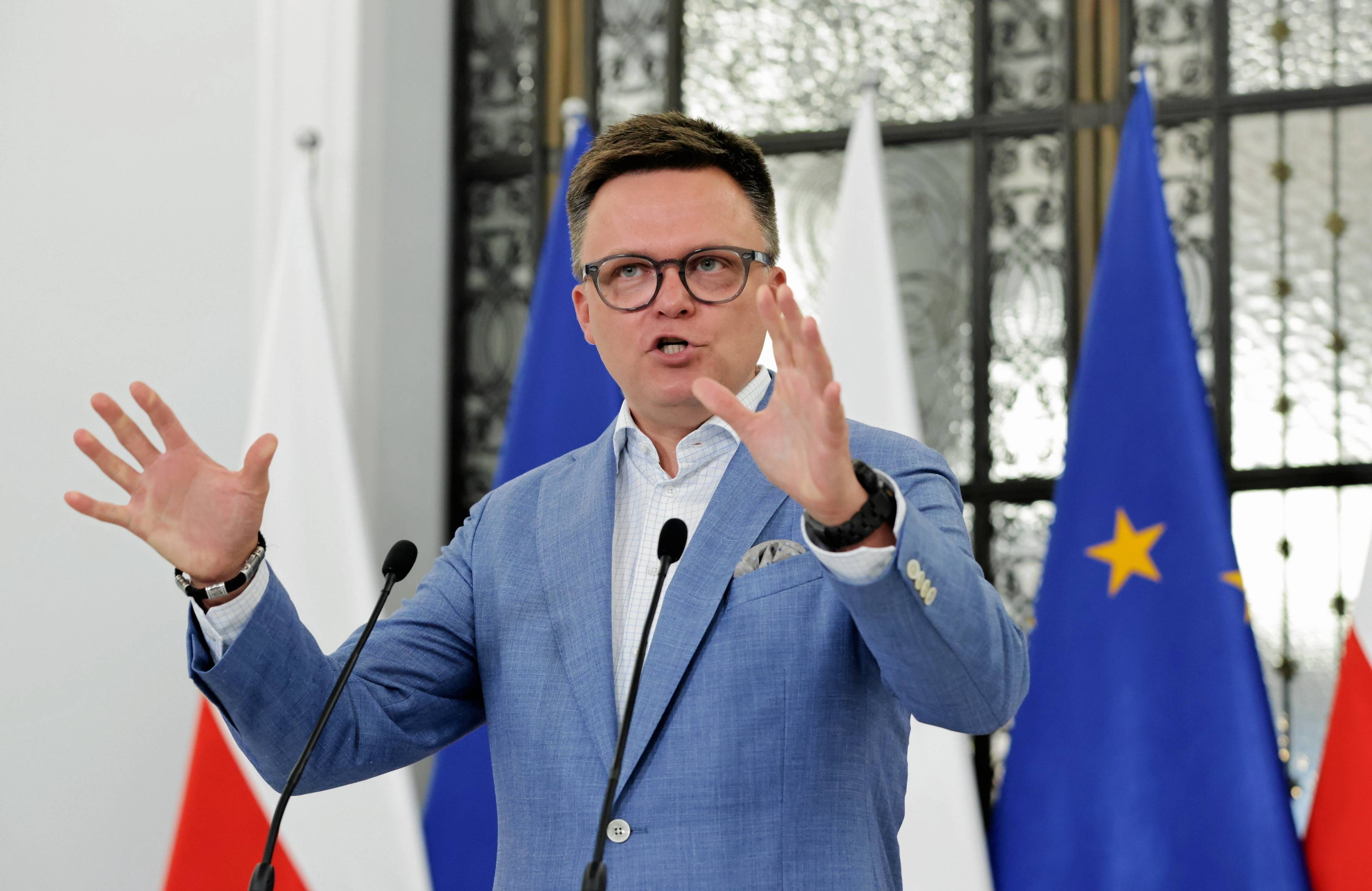 Marszałek Sejmu Szymon Hołownia gestykuluje podczas konferencji prasowej w Sejmie w niebieskiej marynarce